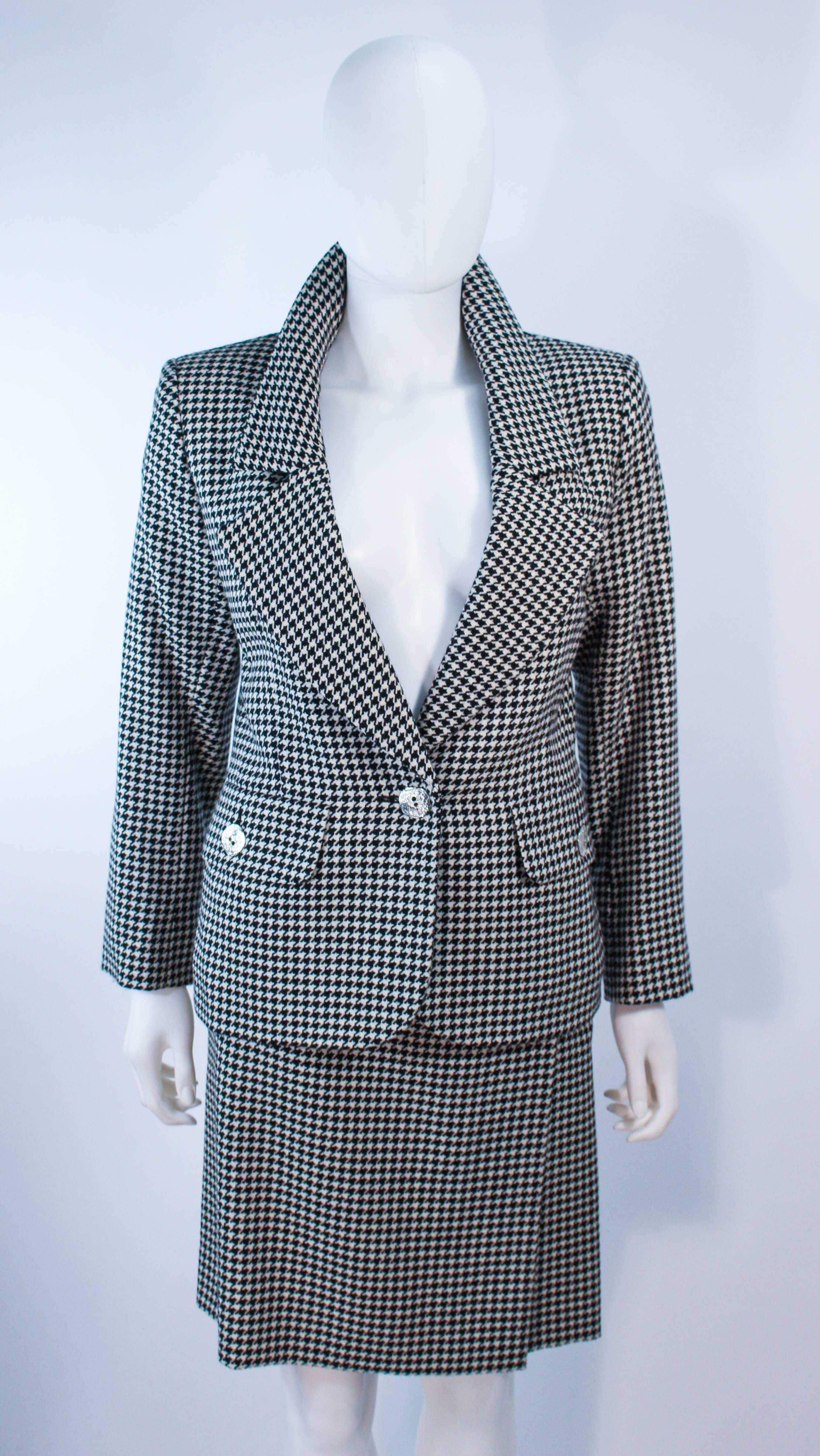 This Yves Saint Laurent skirt suit is composed of a black and white houndstooth wool. The jacket features a center front button closure. The skirt has a zipper closure. In excellent vintage condition.

**Please cross-reference measurements for