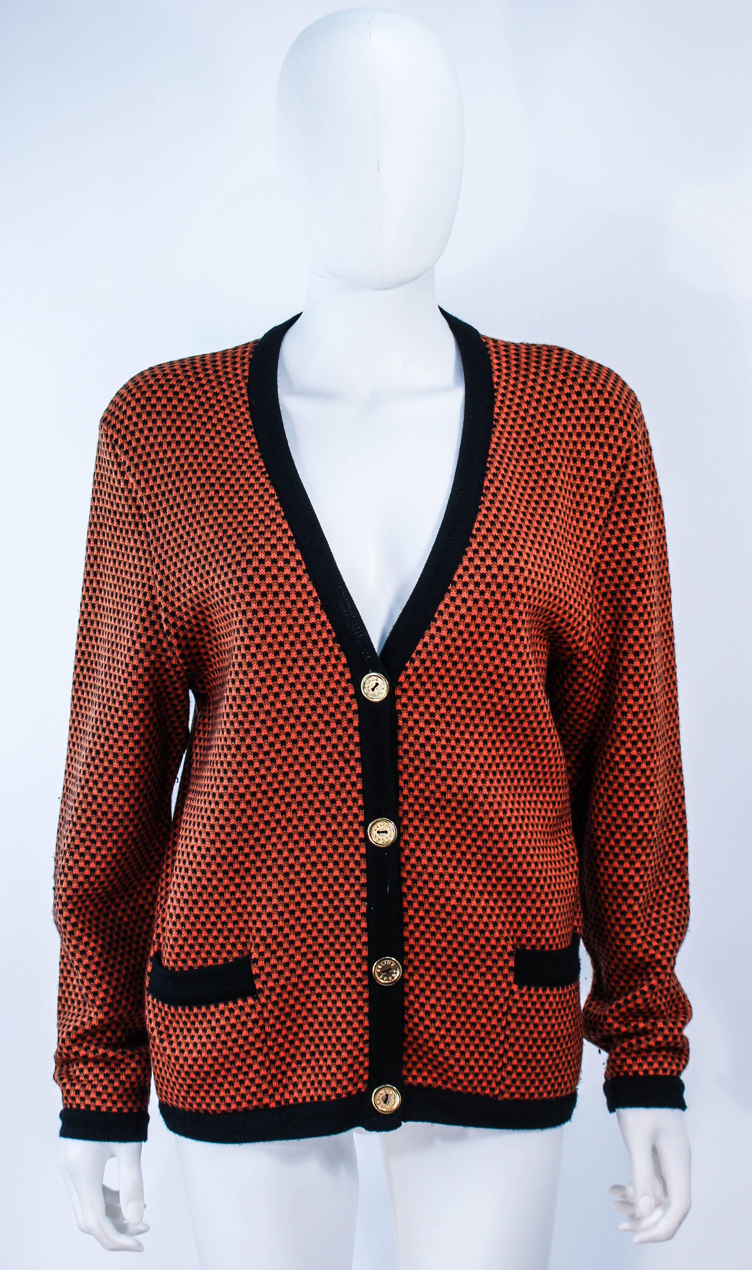 This vintage Celine sweater is composed of a black and orange wool. Features center front gold buttons with front pockets. In excellent vintage condition.

**Please cross-reference measurements for personal accuracy. Size in description box is an