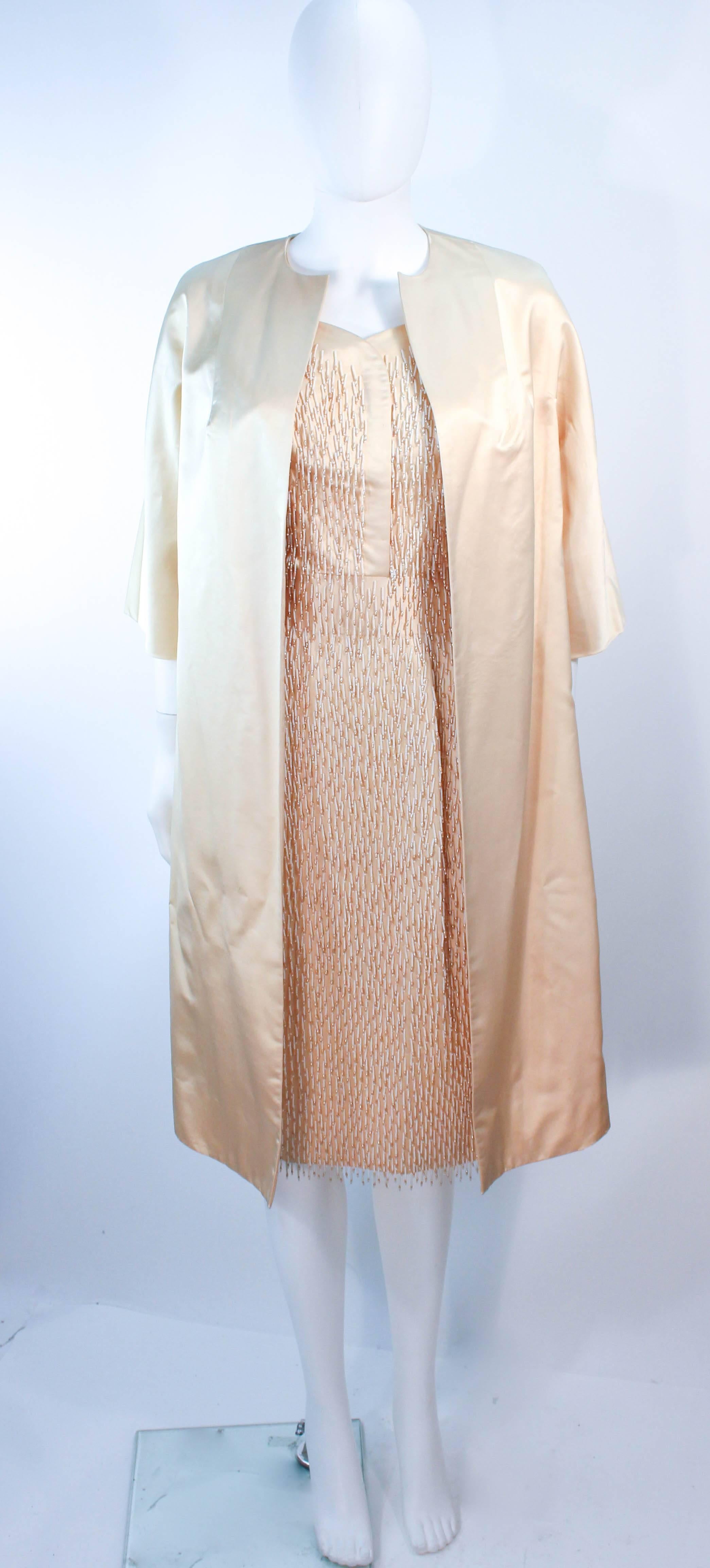 This vintage set is composed of a cream silk and features a cocktail dress with beaded fringe detailing throughout. The dress has a zipper closure. The jacket is a classic open style opera coat. In excellent vintage condition, some discoloration due