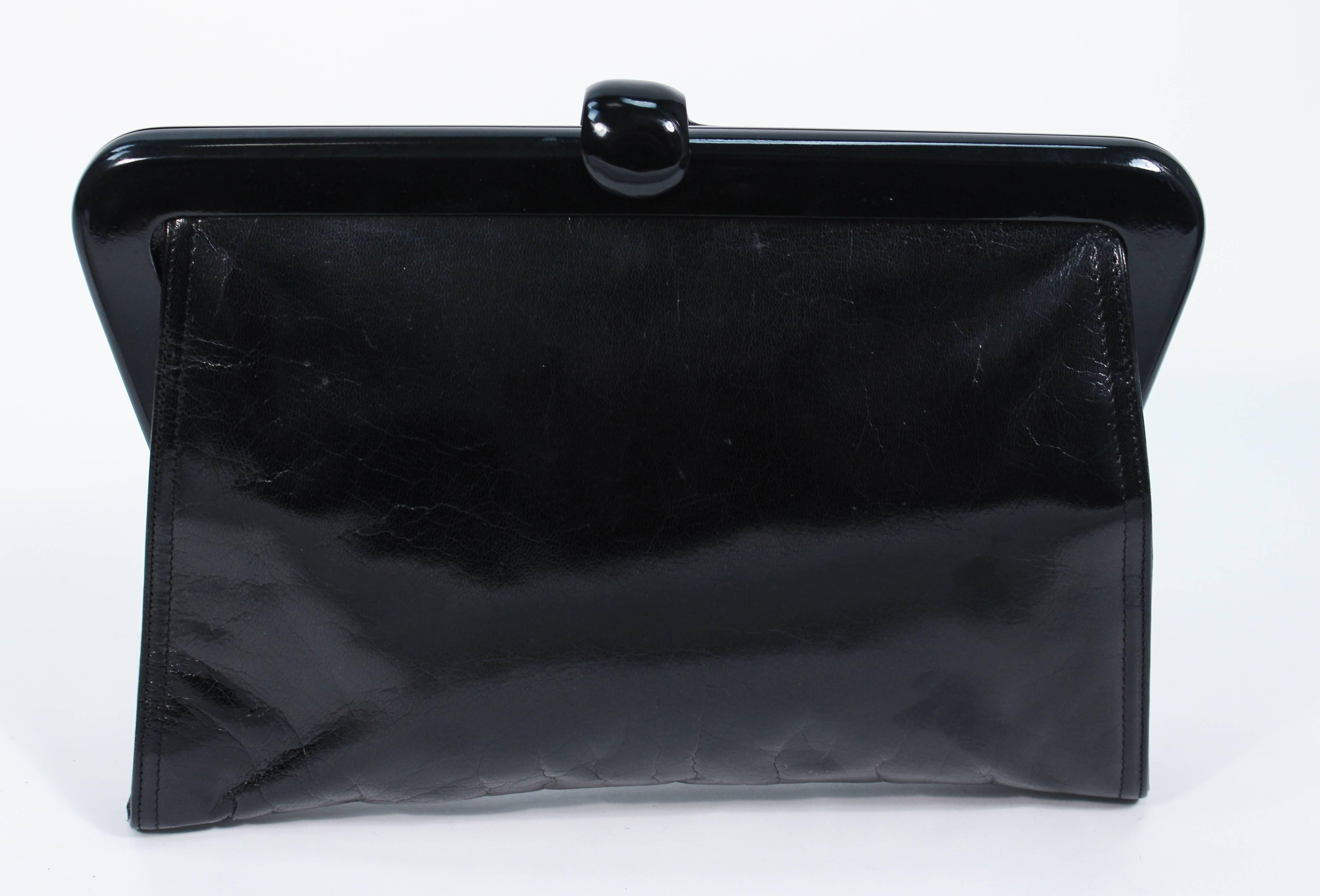 This Bottega Venta purse is composed of a polished black calfskin. Features a lever style clasp. There is an interior zipper compartment. Made in France. In excellent vintage condition, there is some marking on the back of the purse which maybe