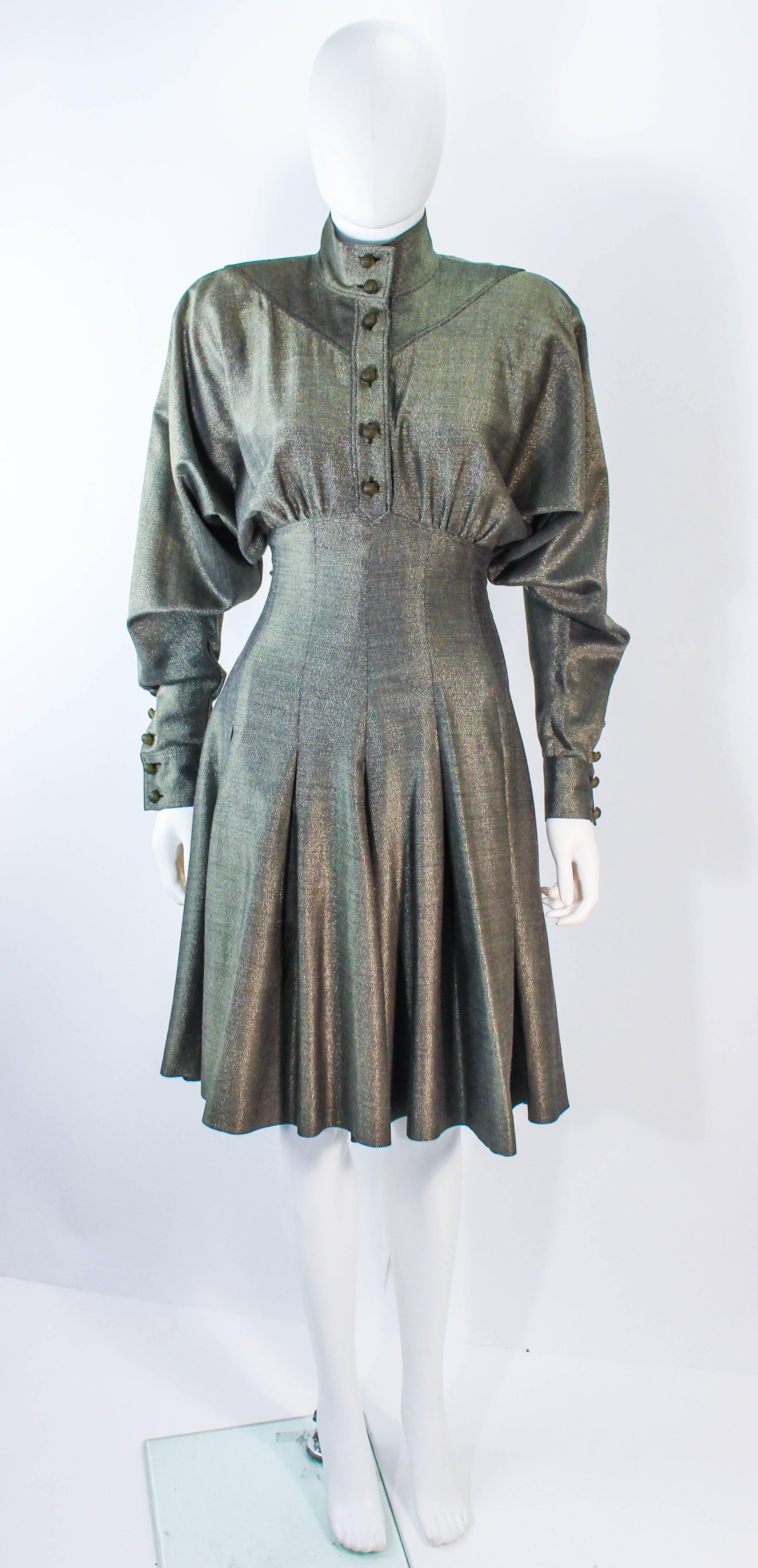 This vintage Fendi dress is composed of a gold and black gunmetal metallic fabric. Features a bat wing design with shoulder pads (can be removed) and a pleated skirt. There is a side zipper closure with center front buttons and buttons at the cuffs.