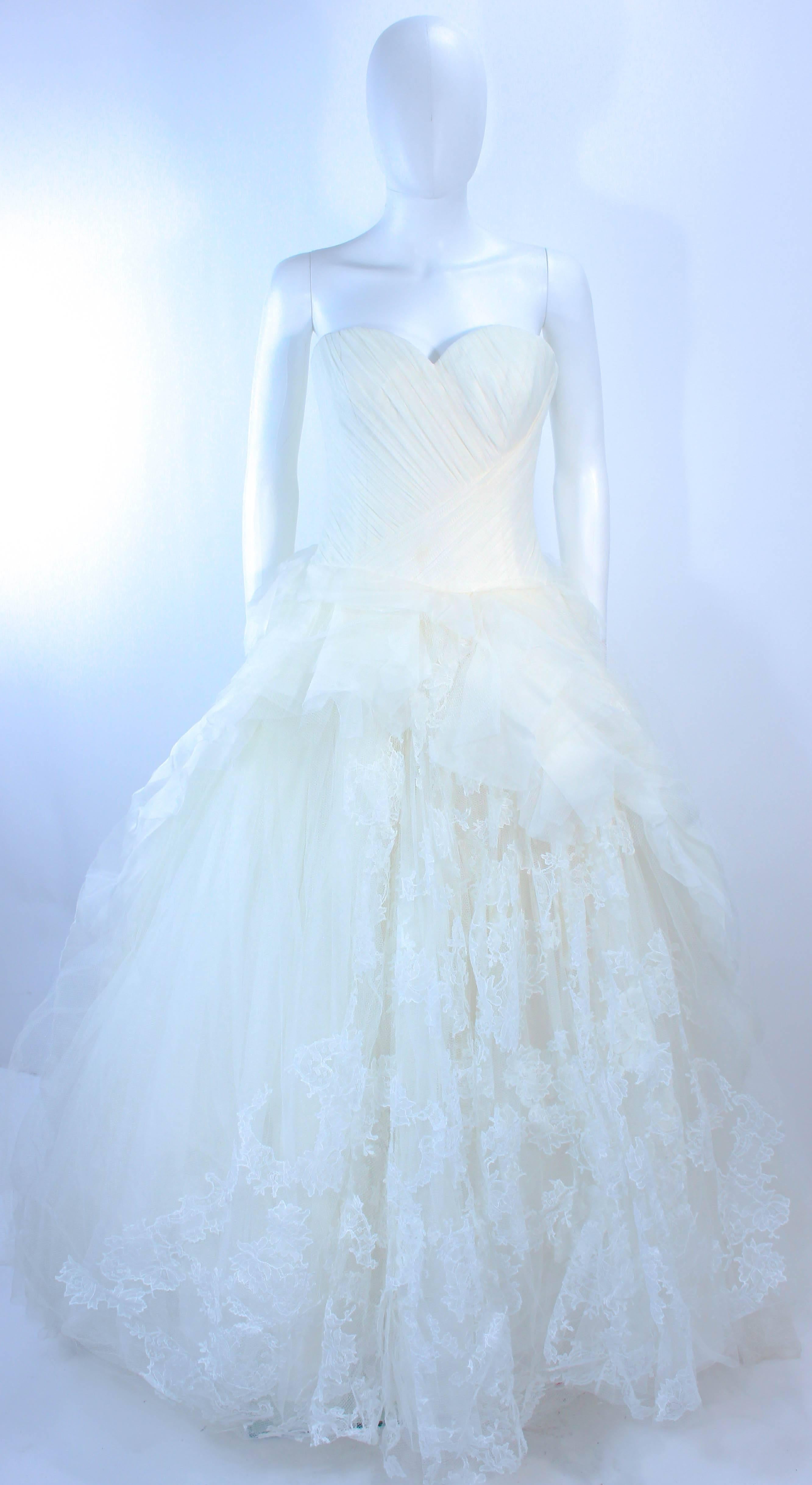 This Vera Wang wedding gown is composed of layers of white tulle and lace . The bodice features a gathered detailing with a boned interior and center back zipper closure. In excellent pre-owned condition (there are a few faint spots due to