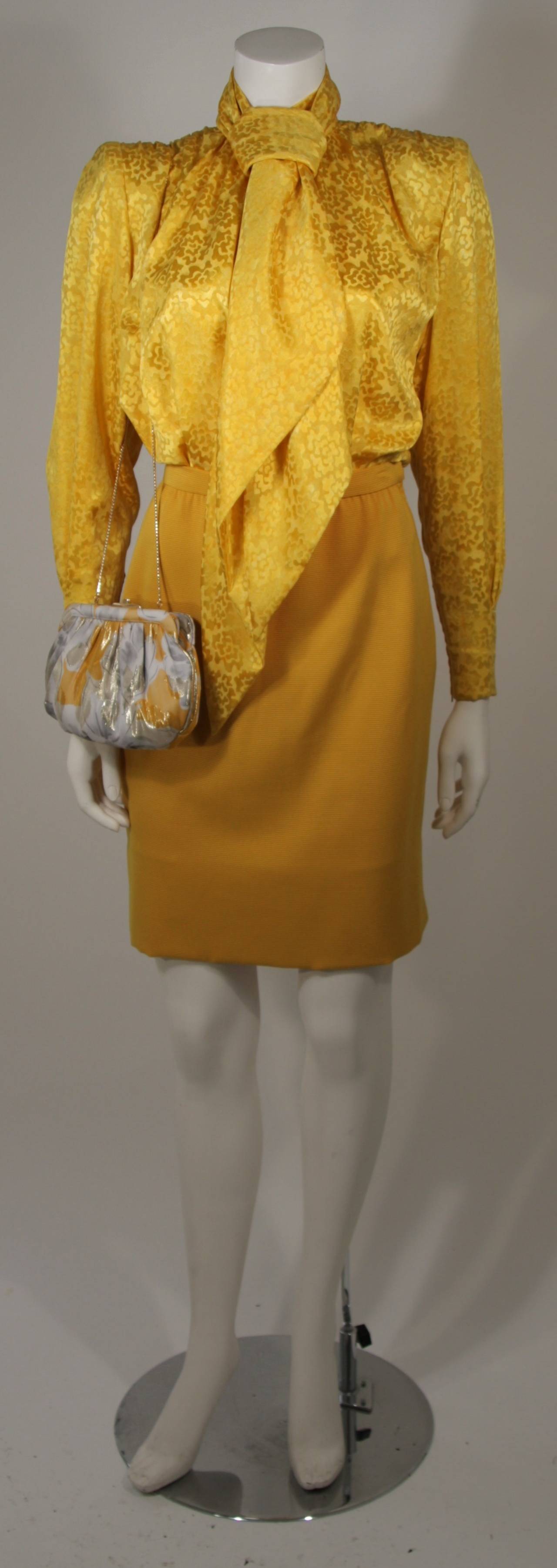 This Galanos and Judith Leiber ensemble is available for viewing at our Beverly Hills Boutique. The ensemble features a silk blouse and matching scarf, a pencil silhouette skirt, and a Judith Leiber purse. The blouse and scarf are composed of a