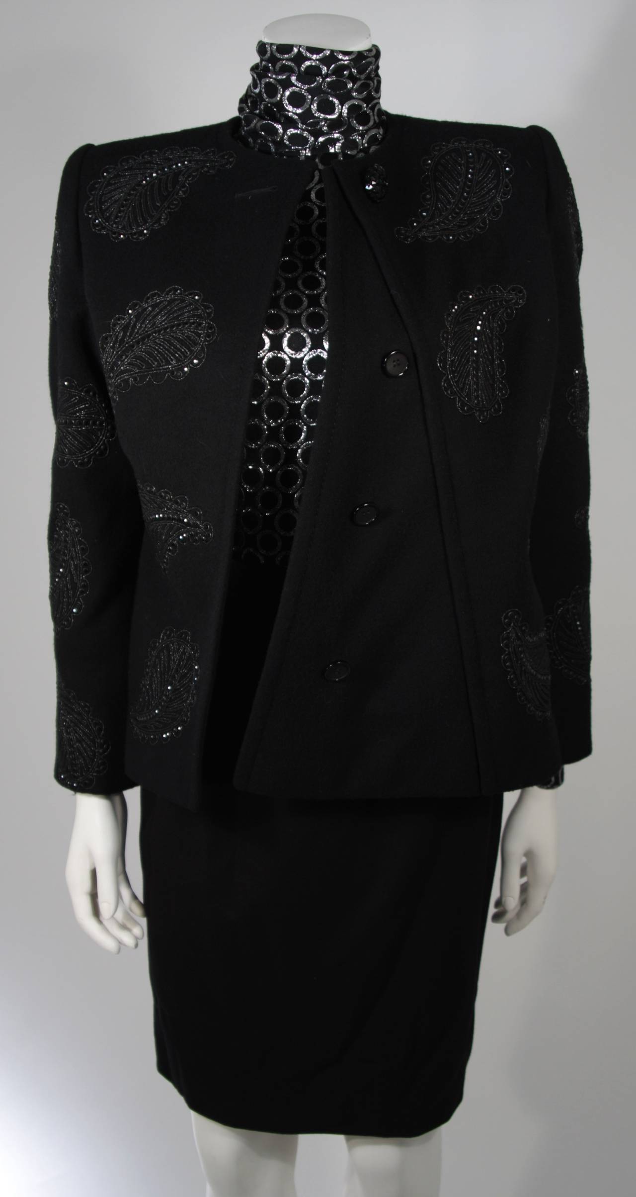 This Galanos ensemble is available for viewing at our Beverly Hills Boutique. The ensemble features three pieces. The jacket and skirt are composed of a black wool. The jacket has a metallic thread embroidered paisley design with black rhinestone
