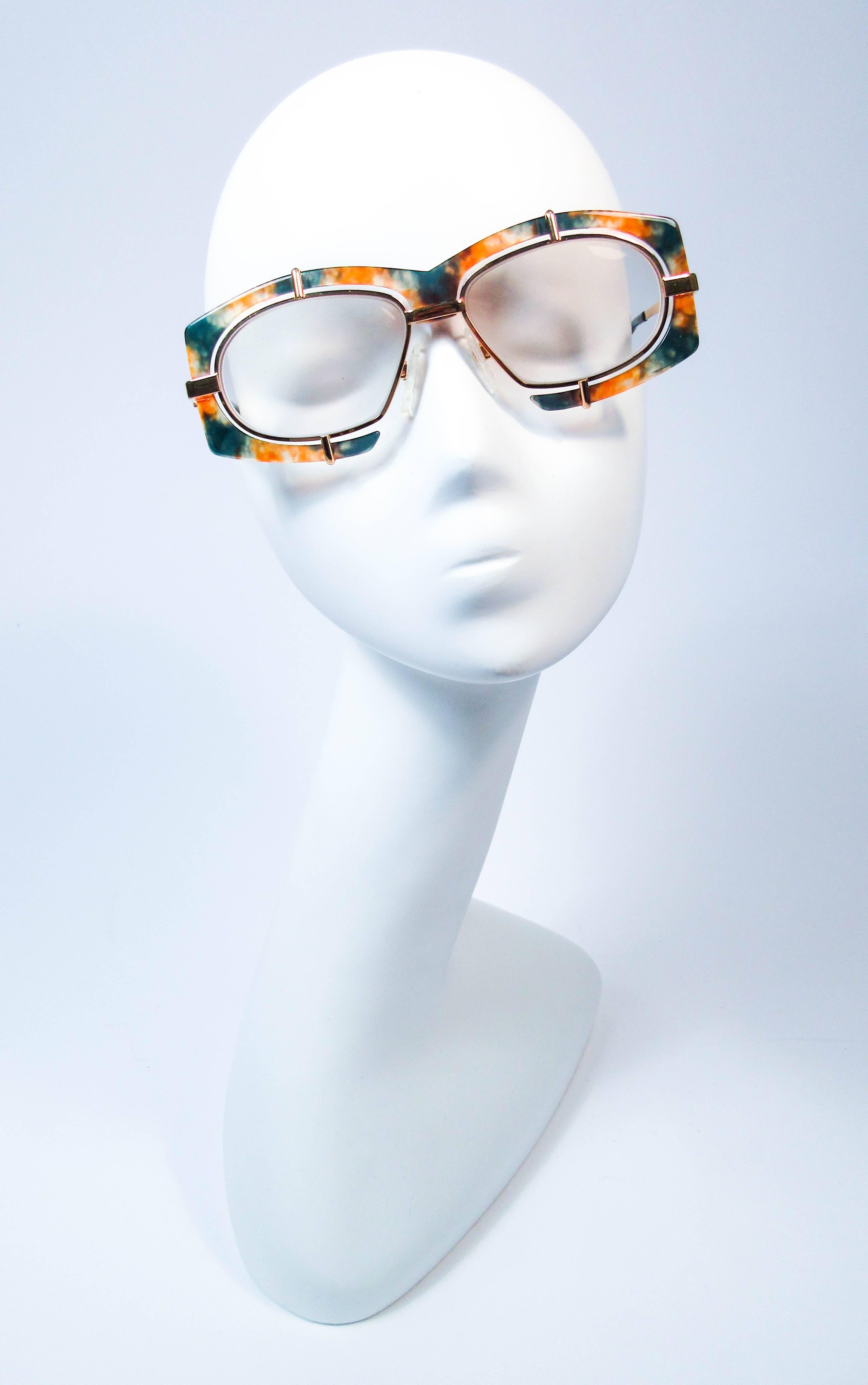 These Cazal glasses are composed of a orange and green plastic set, floating with in a gold tone metal frame. Features gold legs with Cazal logo. In great vintage condition, lenses are prescription and can be easily replaced.

**Please