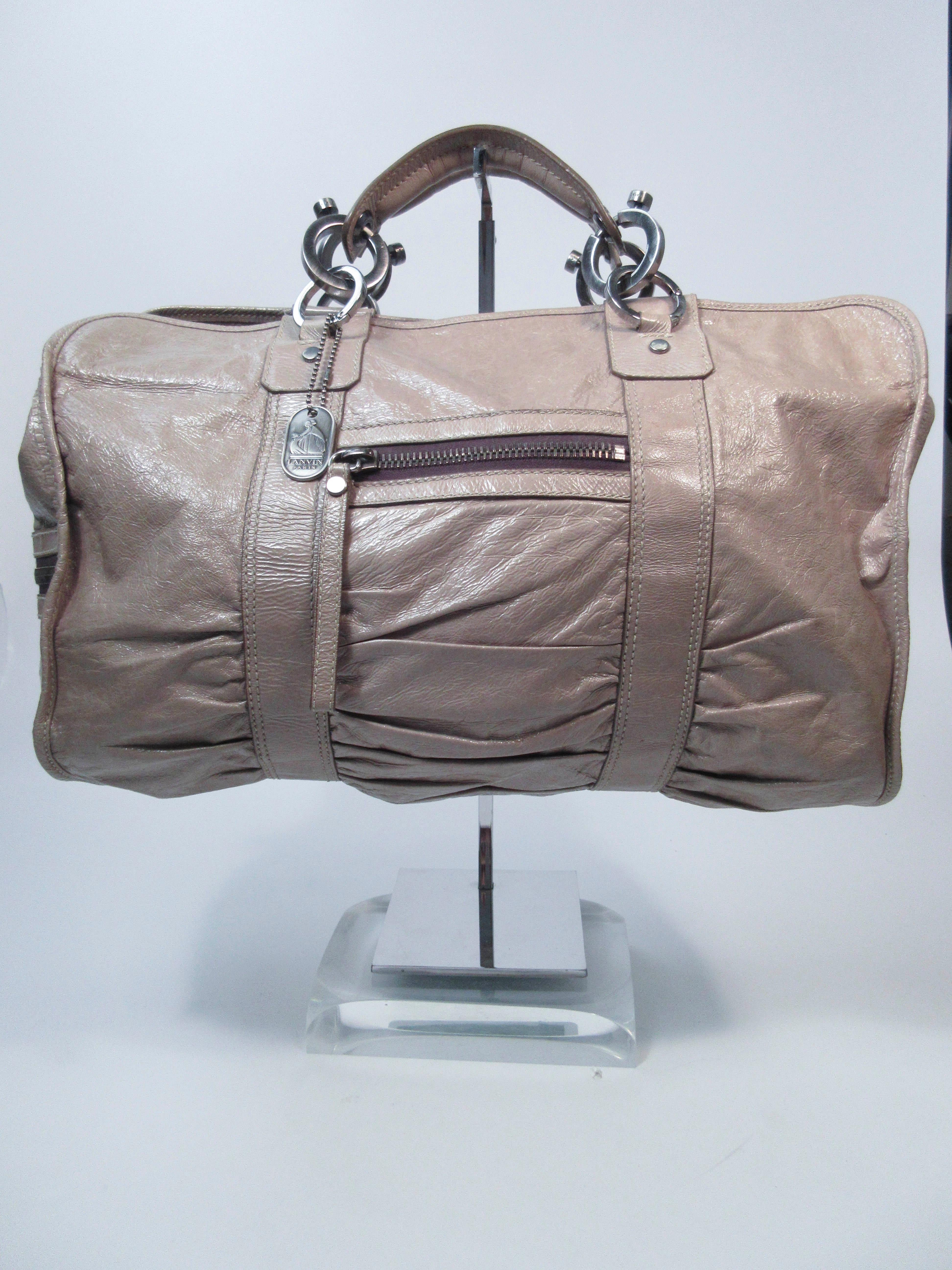 This Lanvin is composed of a taupe patent leather with silver-tone hardware & mechanism. Features exterior zipper pockets with two interior slide pockets. In used pre-owned condition (signs of wear due to age, and heavy interior use/marks, see