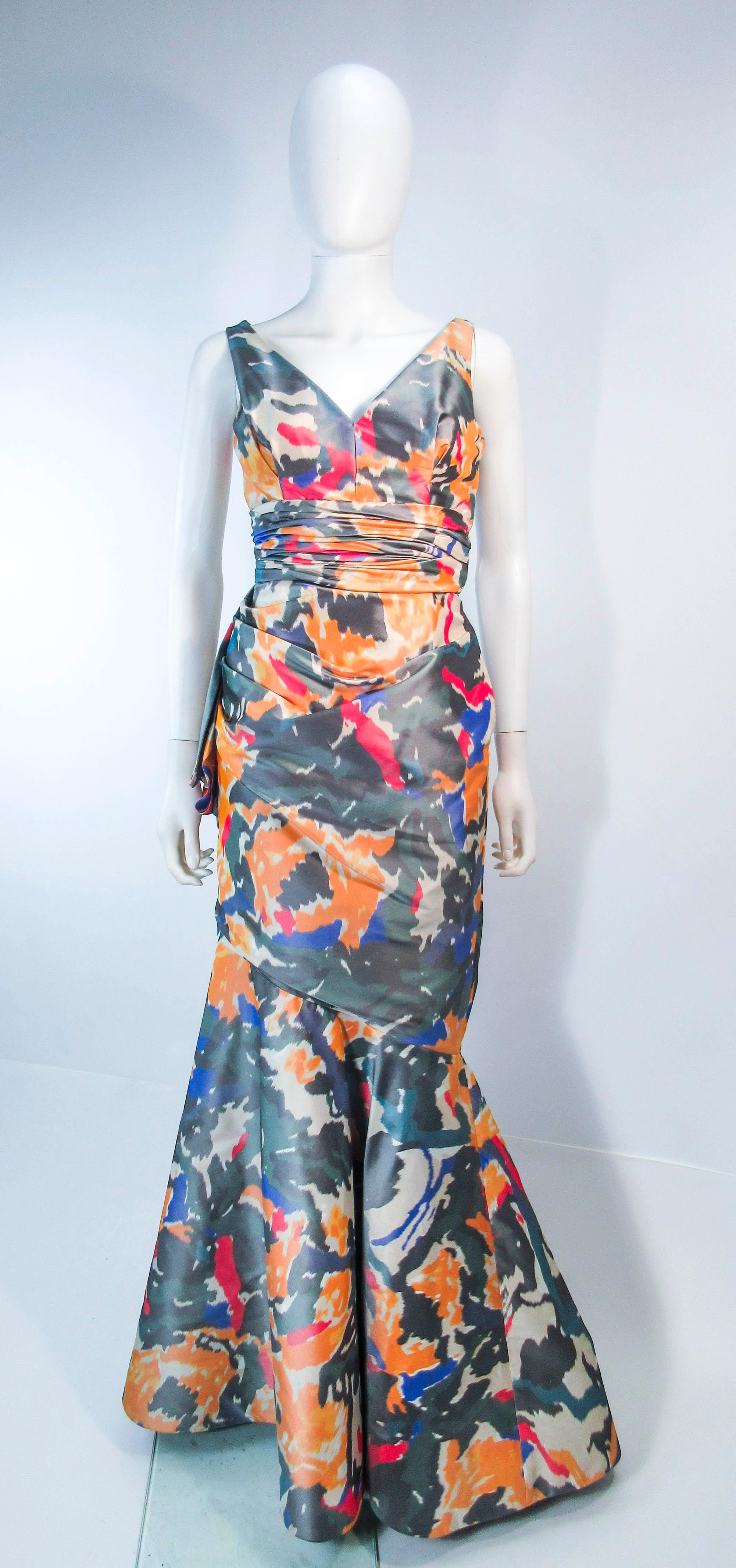 This Oscar De La Renta gown is composed of silk in an Ikat print with hues of grey, yellow, red, & blue. Features a v-neck design with a flared knee to hem design and gathered waist. There is a side zipper closure. In excellent vintage