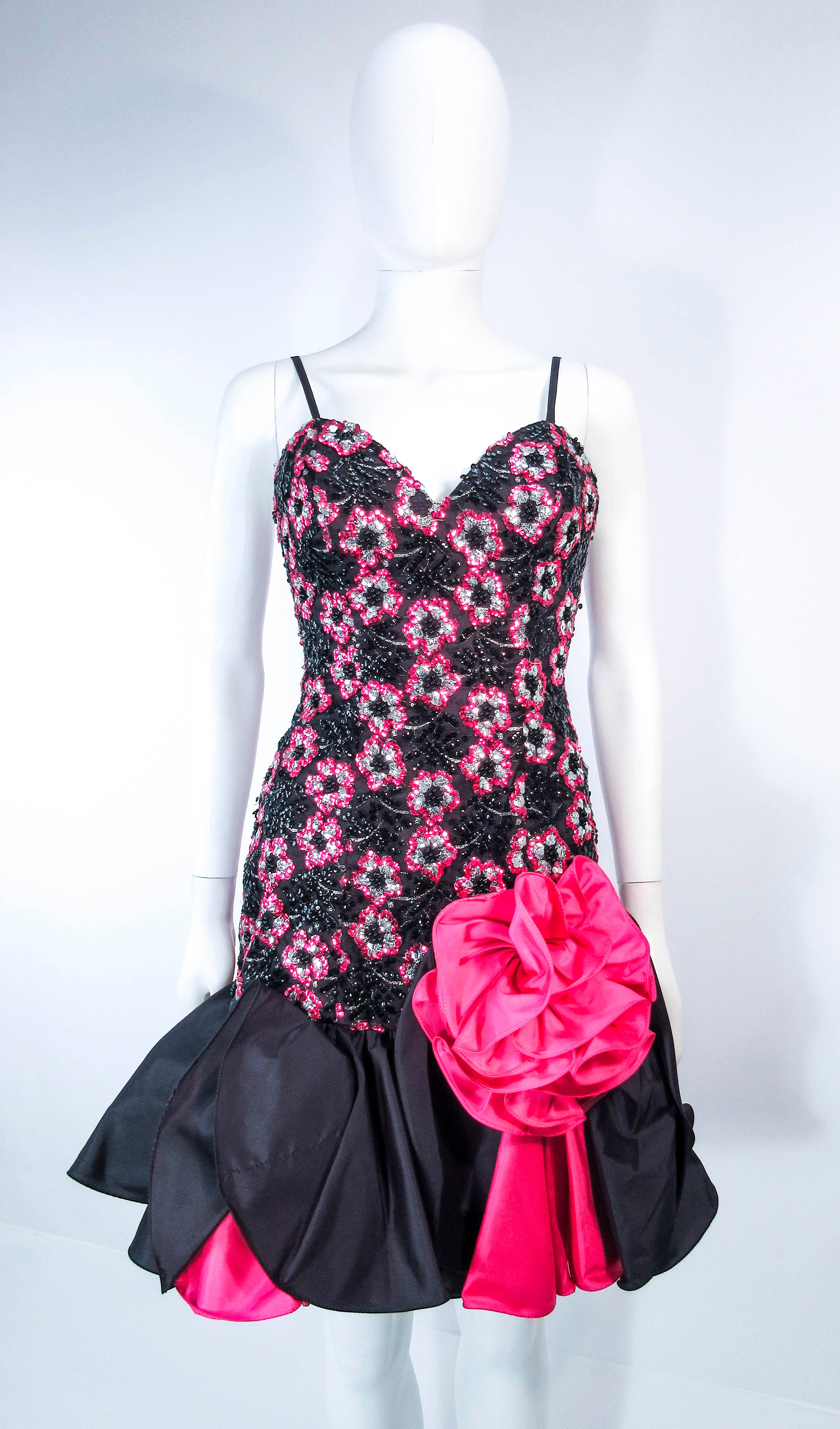 This vintage 1980's cocktail dress is composed of black and pink sequins with cascading ruffles throughout. Features spaghetti straps and a large front flower applique form fitting shape to the flared hem. There is a center back zipper closure. In