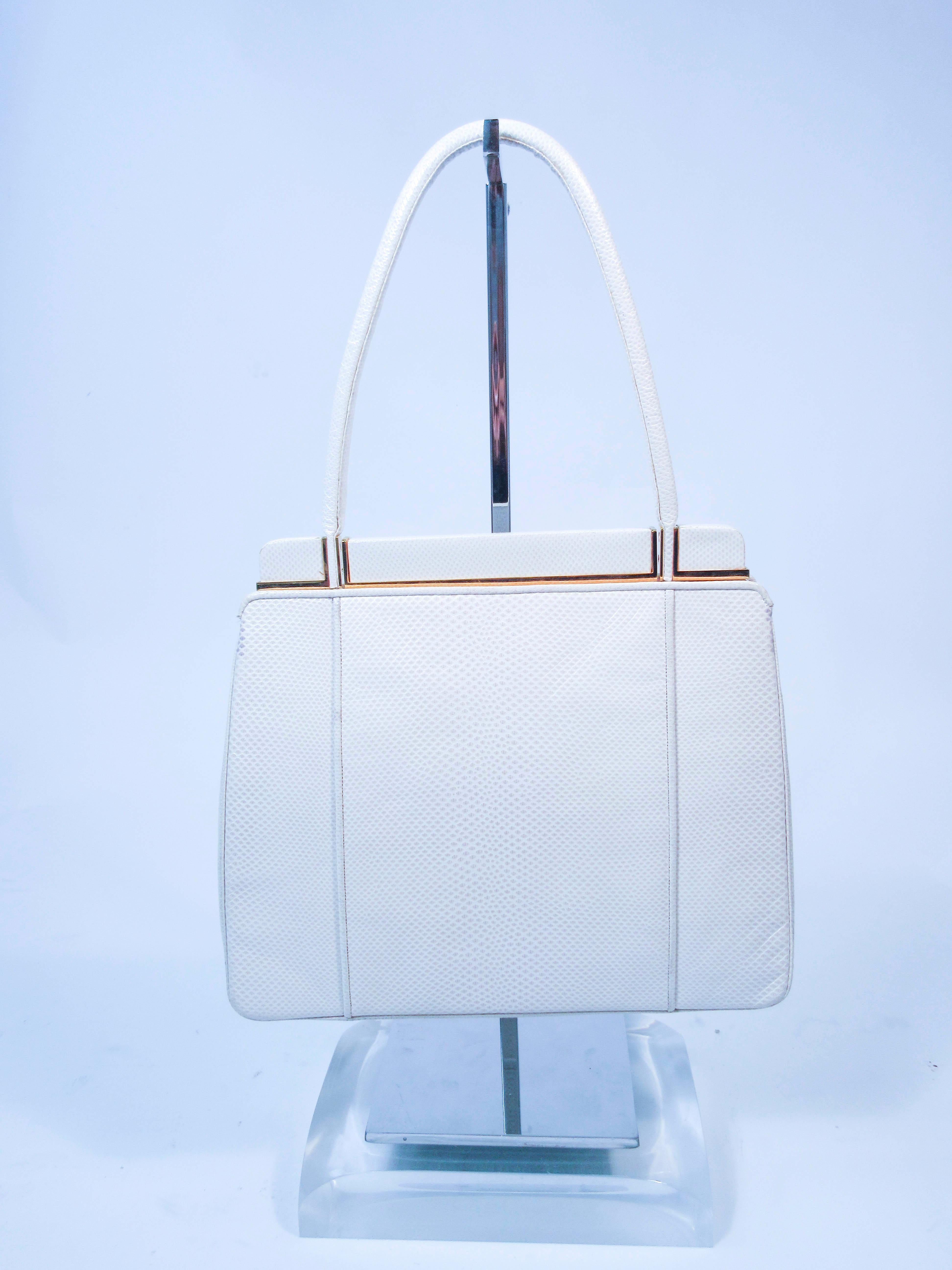 This Judith Leiber purse is composed of a white lizard with goldtone hardware.  Comes with an optional strap. There is an interior zipper pocket. In excellent almost new vintage condition (some signs of wear due to age, see photos, some glue