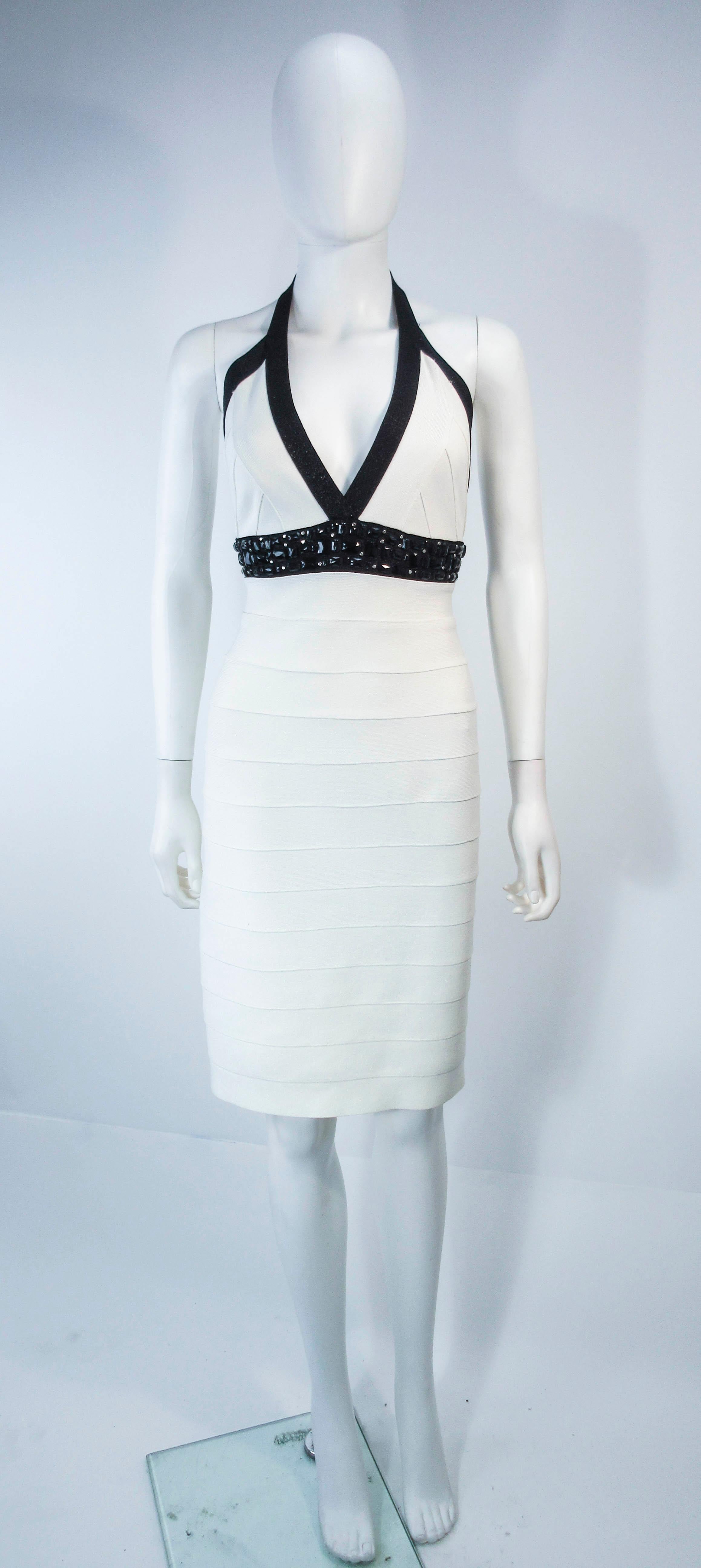 This Herve Leger is composed of a white metallic elastic with black trimming. Features a beaded empire waist. There is a center back zipper closure. In excellent pre-owned condition, some wear (see photos). 

**Please cross-reference measurements