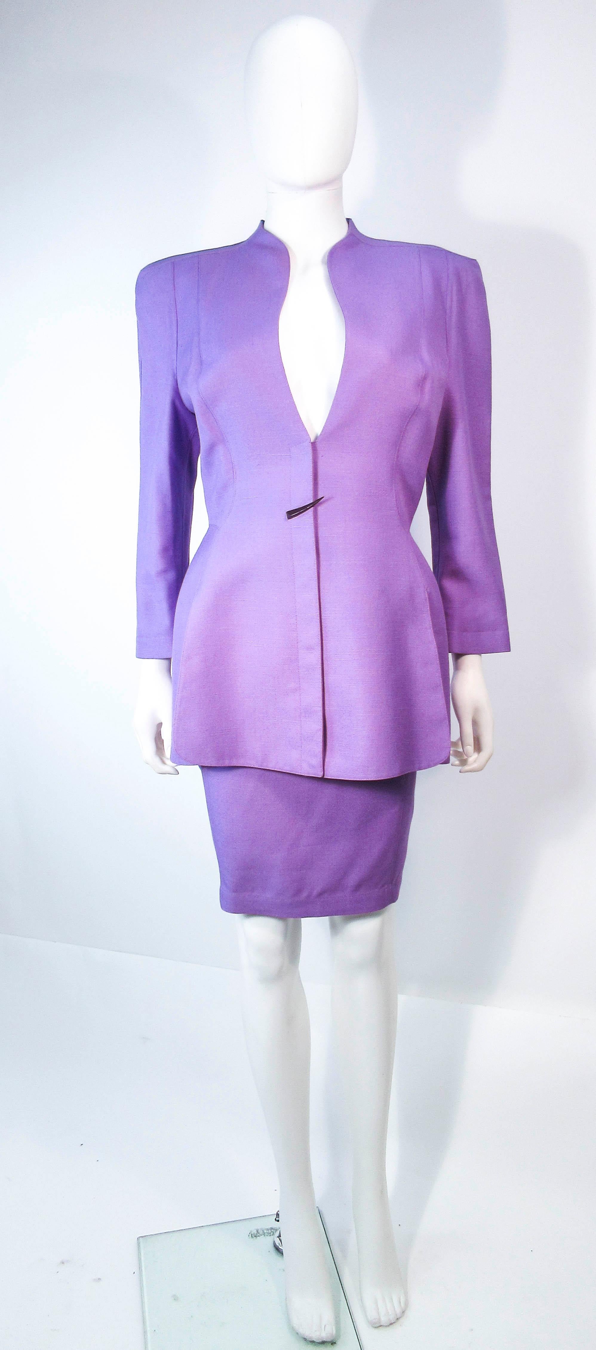  This Thierry Mugler skirt suit is composed of a lavender/purple hue fabric. Features a classic Mugler silhouette with nipped waist and curved bust-line to neckline design. The classic pencil style skirt features a zipper closure. In good vintage