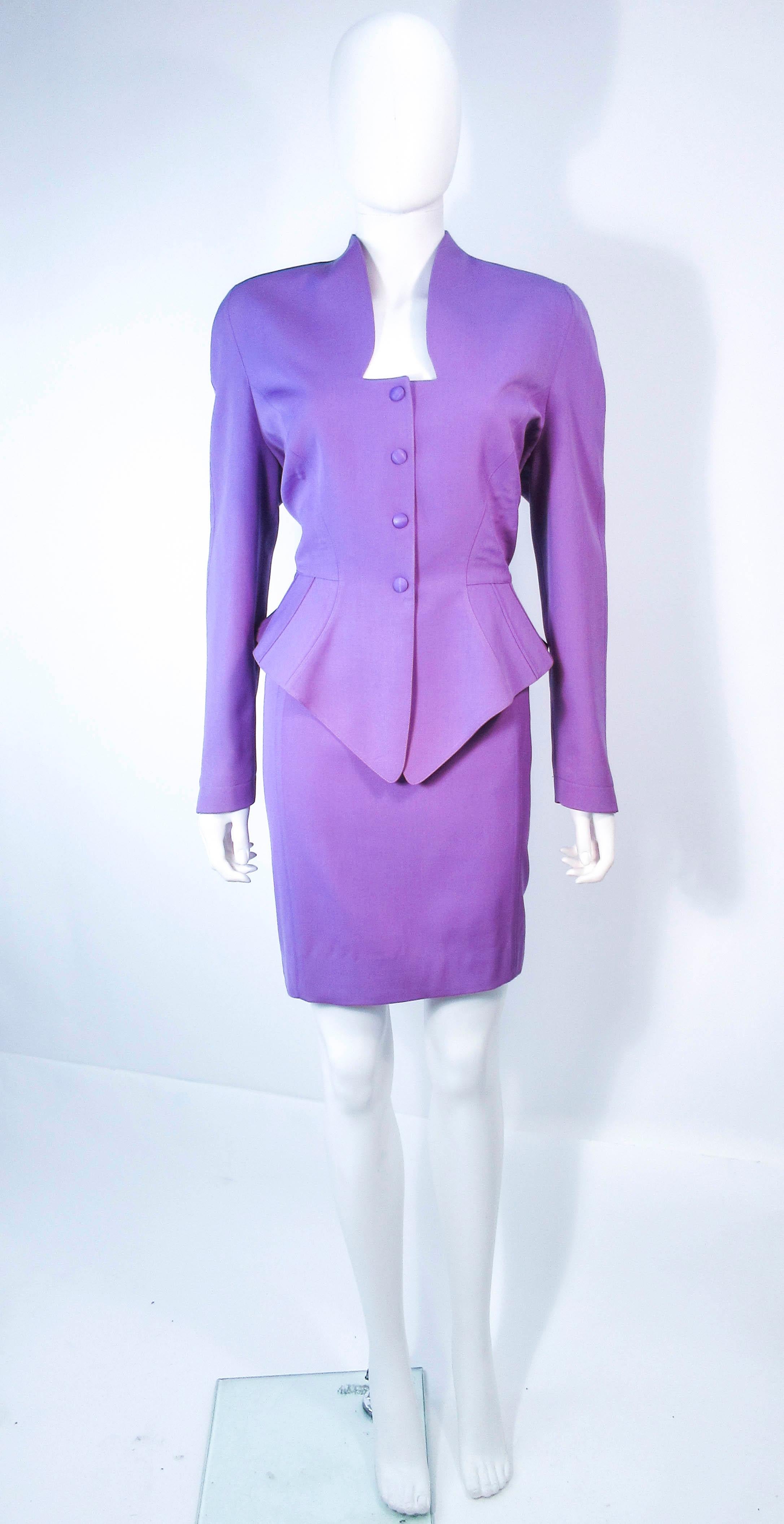  This Theirry Mugler skirt suit is composed of a lavender/purple hue wool. The jacket features a peplum design with snap front closures. The classic pencil style skirt features a zipper closure and appears to have been previously altered. 
 Made in