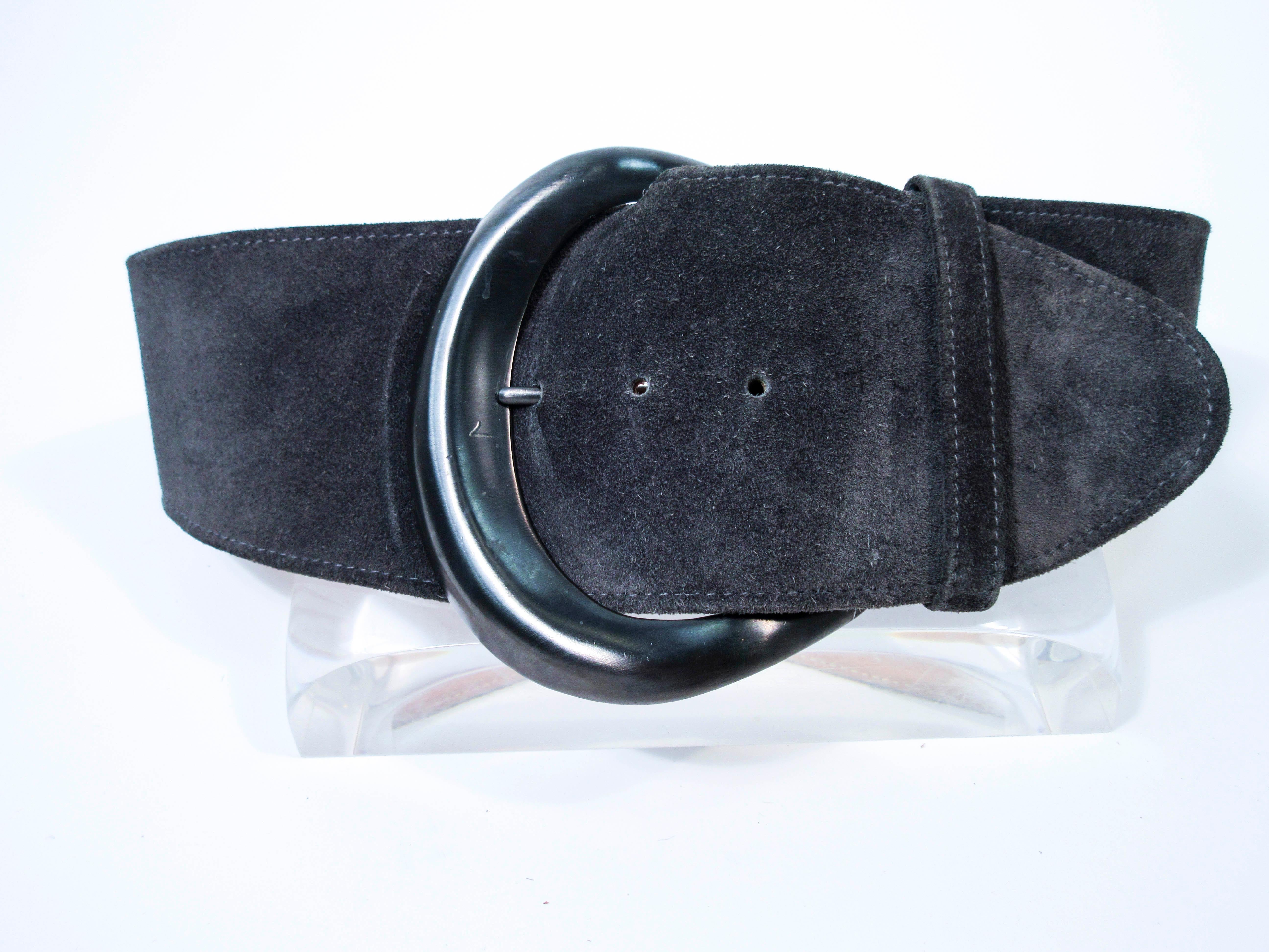 This vintage Donna Karan belt is composed of a grey suede with large gunmetal hue buckle. Features a classic wide style high waist style. This is a fantastic statement piece and excellent addition to any collectors wardrobe. In excellent pre-owned
