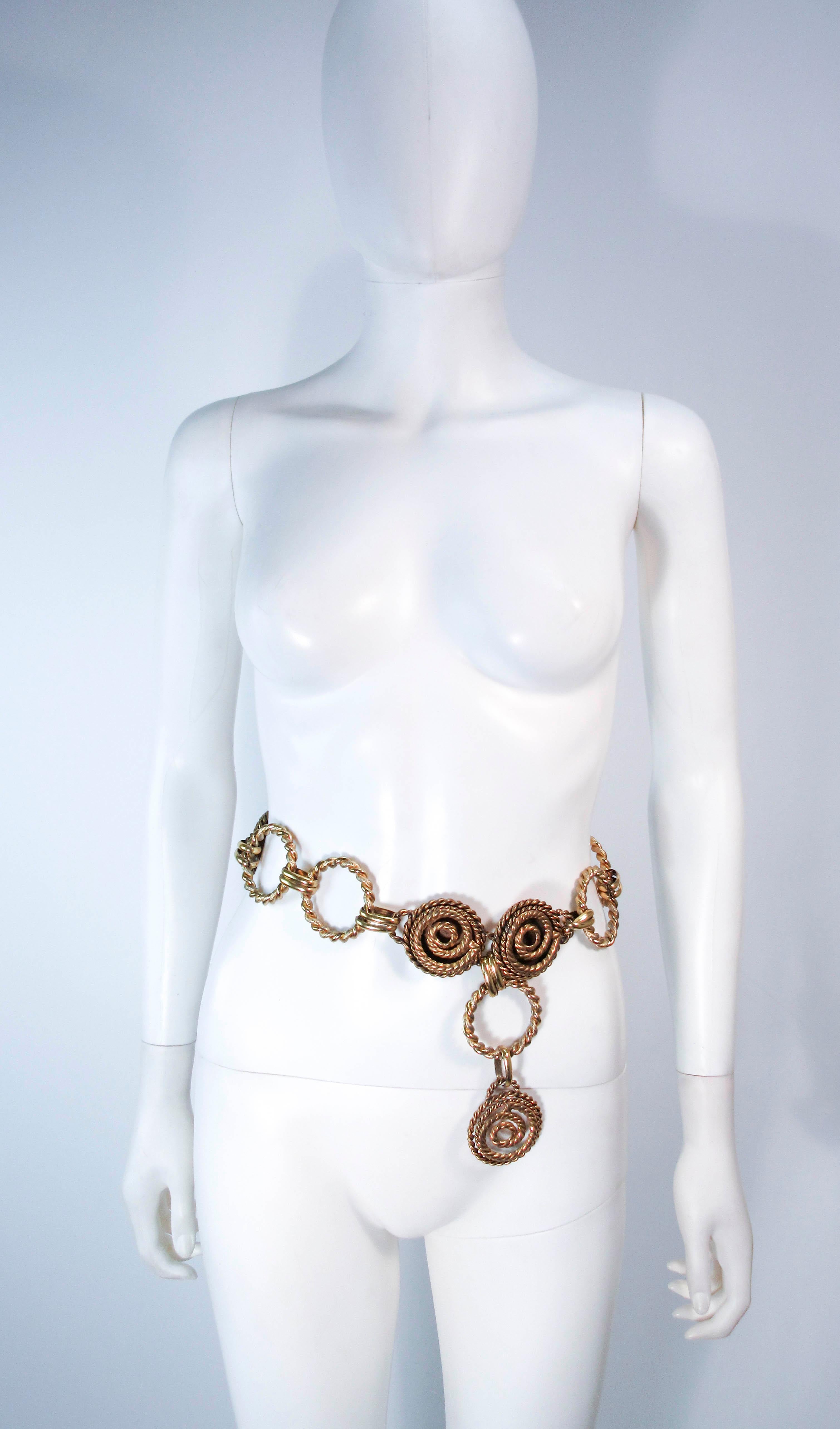 This vintage Butler & Wilson gold tone belt feature a swirl design and dangle style. This is a fantastic statement piece and excellent addition to any collectors wardrobe. In excellent vintage condition (some signs of wear due to age, see photos).
