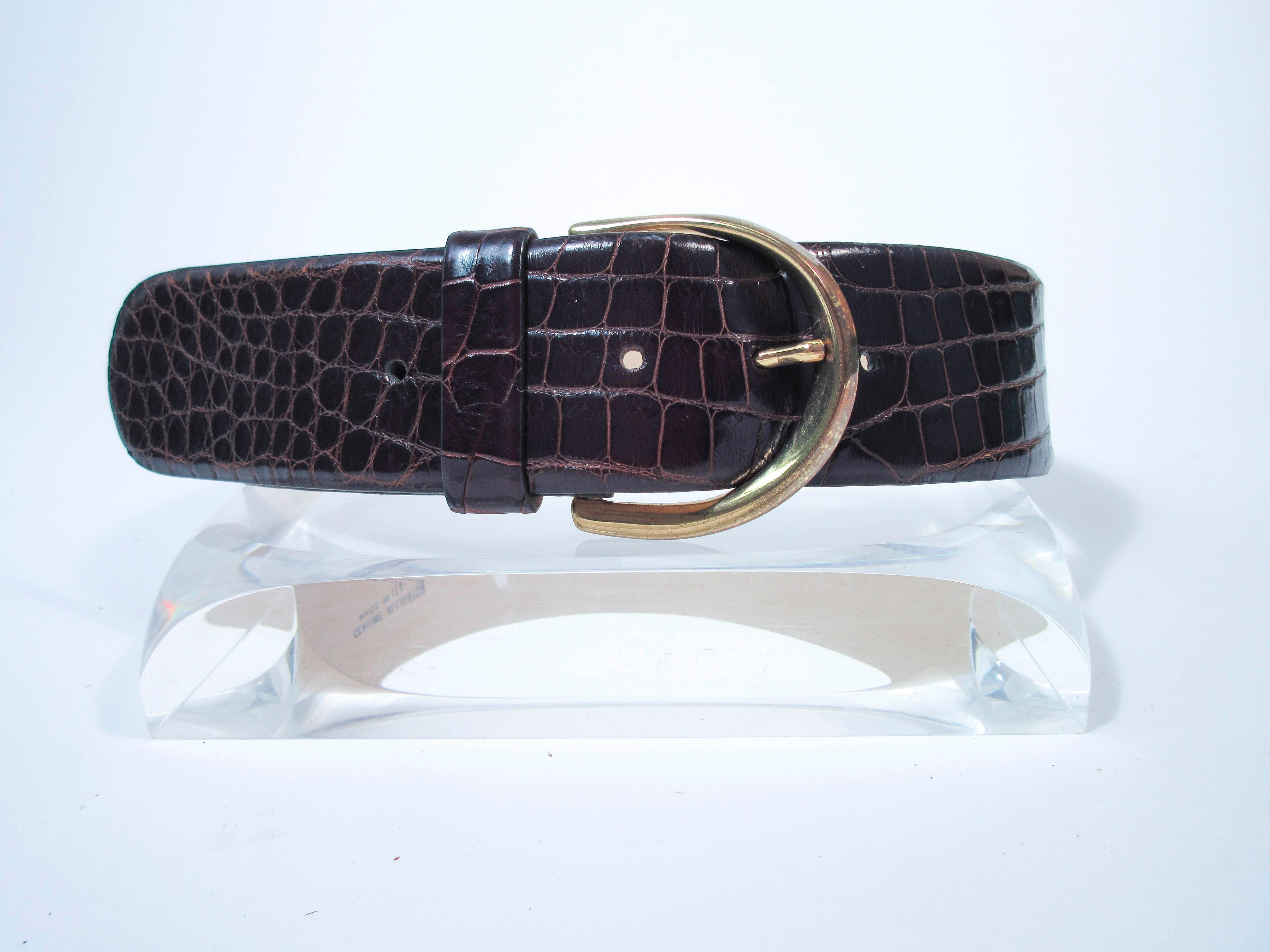 This Donna Karan belt is composed of a brown alligator. Features a classic wide style high waist style with gold tone hardware. This is a fantastic statement piece and excellent addition to any collectors wardrobe. In excellent pre-owned condition