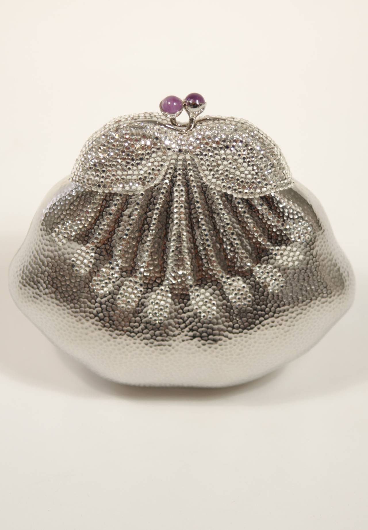 This Judith Leiber design is available for viewing at our Beverly Hills Boutique. We offer a large selection of evening gowns and luxury garments.

This evening clutch is composed of a silver hued metal and features an Aubergine hued closure while