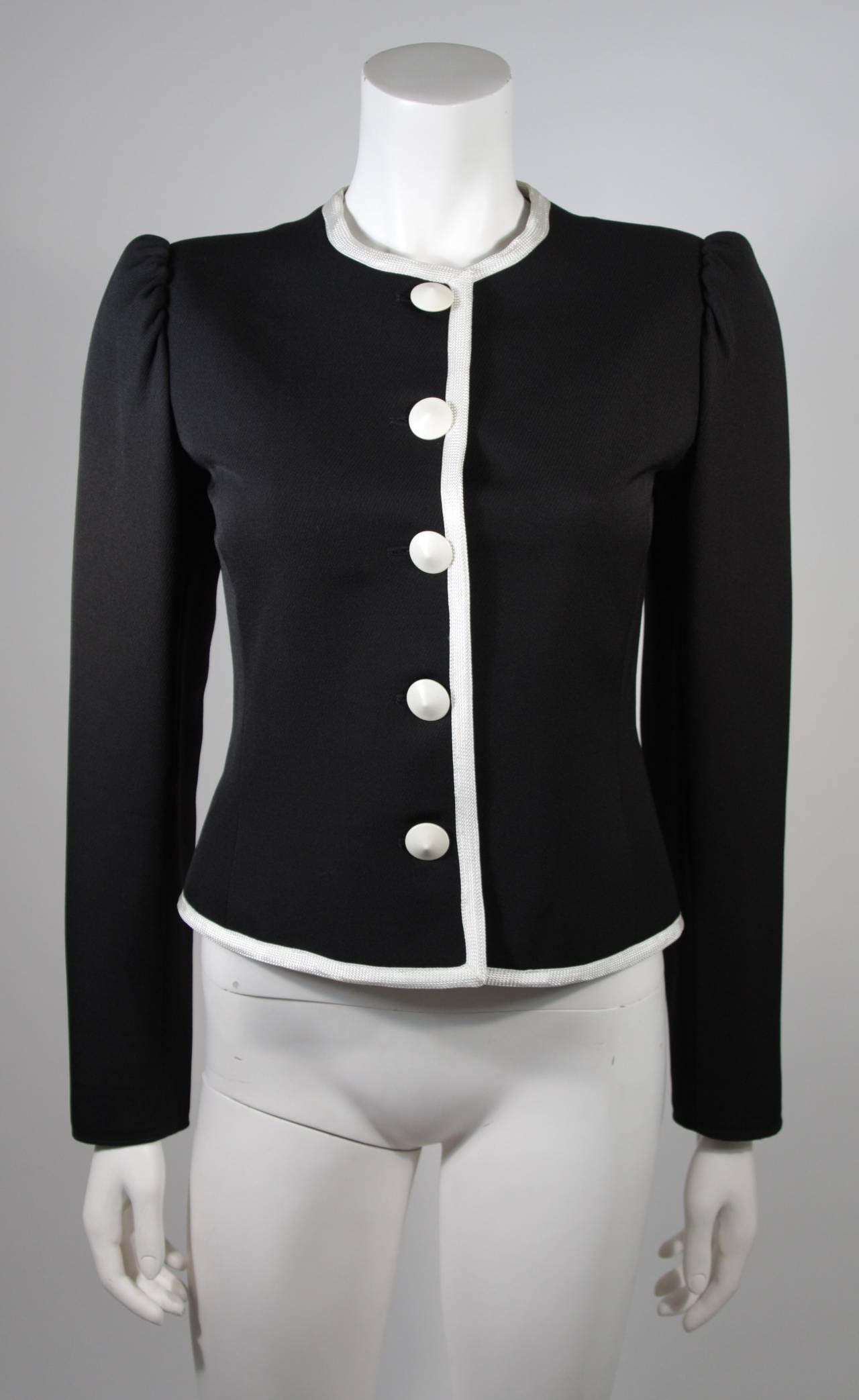 This Yves Saint Laurent jacket is composed of black wool blend with white trim. There are center front faceted buttons. Made in France. 

Measures (Approximately)
Length: 20