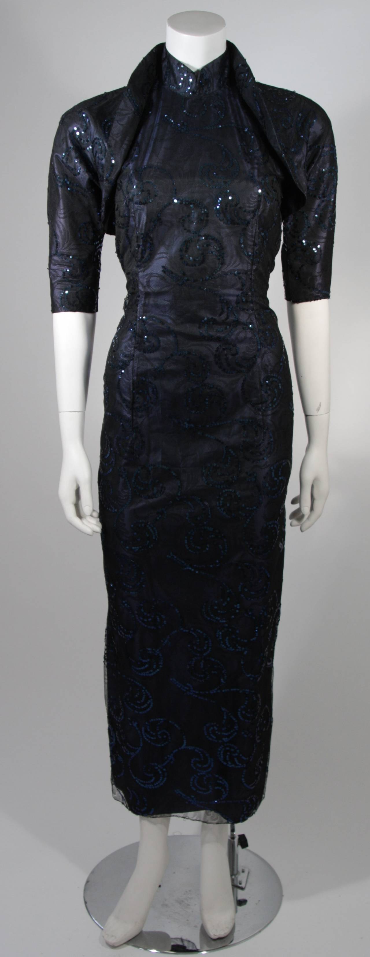 This Asian inspired set is composed of deep sapphire silk with a black net overlay and hand applied sequins. The bolero has a snap option attach to the gown. The gown features a mandarin neckline and zipper closure. The set is in good