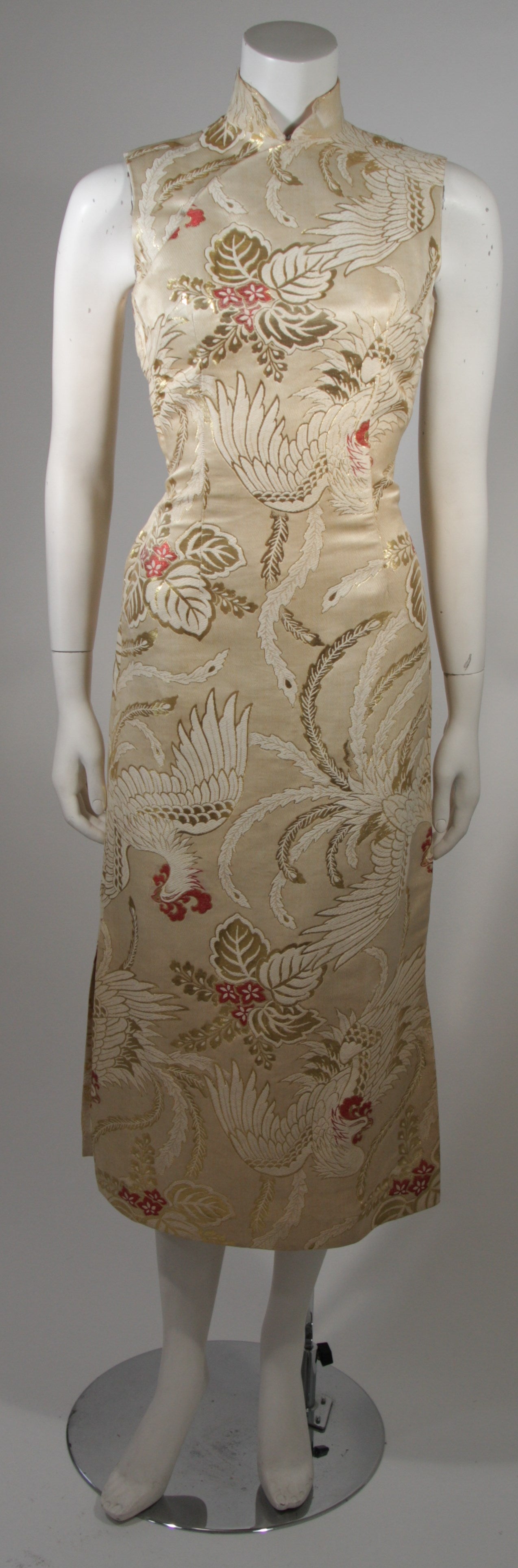 This custom made 1950's cocktail dress is composed of an ivory, cream, and gold Brocade silk with red accents. The dress features a Phoenix pattern. There is a metal side zipper closure and Mandarin neckline and side slits for ease of