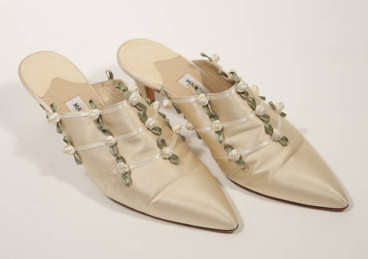 This Manolo Blahnik shoes are composed of an ivory silk and feature floral silk accents. In good condition, shows wear on soles. Made in Italy.

Measures (Approximately)
Insole Length: 9.25