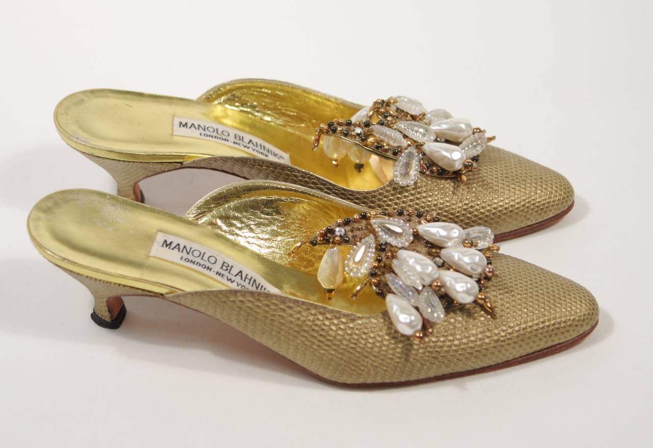 These Manolo Blahnik shoes are composed of a gold embossed leather with a lizard patterning. They are accented with cascading pearls and beads. In good condition, shows wear on sole. Made in Italy.

Measures (Approximately)
Insole Length: