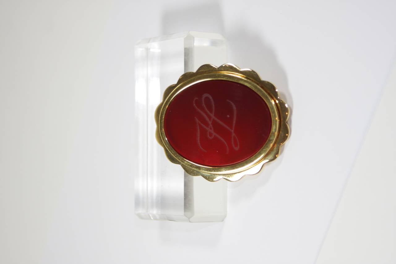 This Karl Lagerfield design is available for viewing at our Beverly Hills Boutique. We offer a large selection of evening gowns and luxury garments.

This brooch is composed of gold tone metal
and features a red glass center piece with engraved