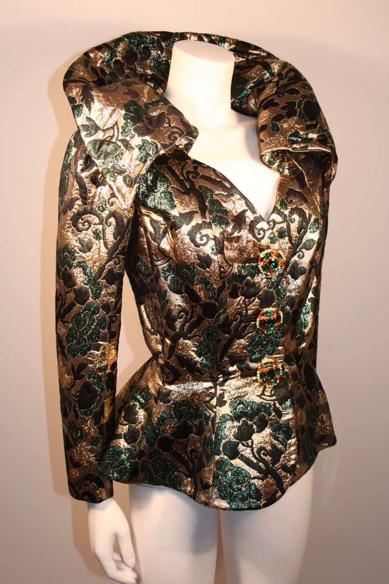 This is an absolutely amazing green and gold couture skirt suit by Yves Saint Laurent. The suit is made with a beautiful metallic brocade fabric. Designed with a feminine shape in mind, this piece features a wonderful collar which can be worn up or