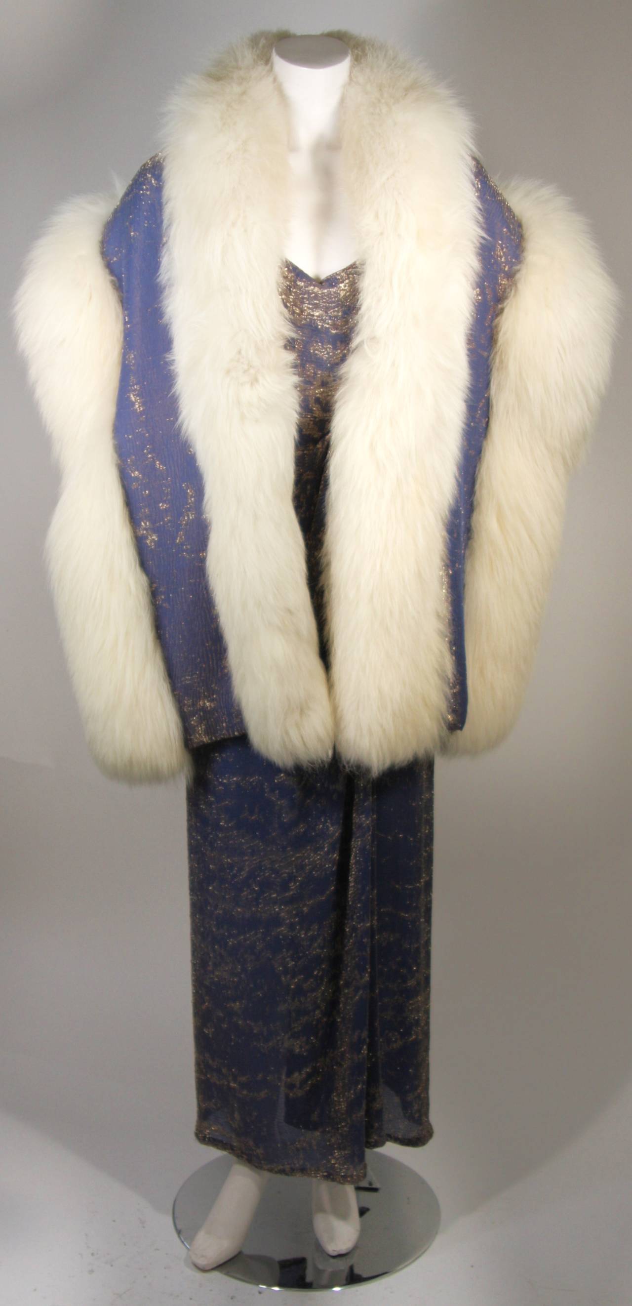This Nolan Miller attributed gown with wrap ensemble is composed of a slate blue silk and gold lame. The gown is in excellent condition and features a center back zipper. The large wrap is in need of reconstruction, the fur is in poor condition and