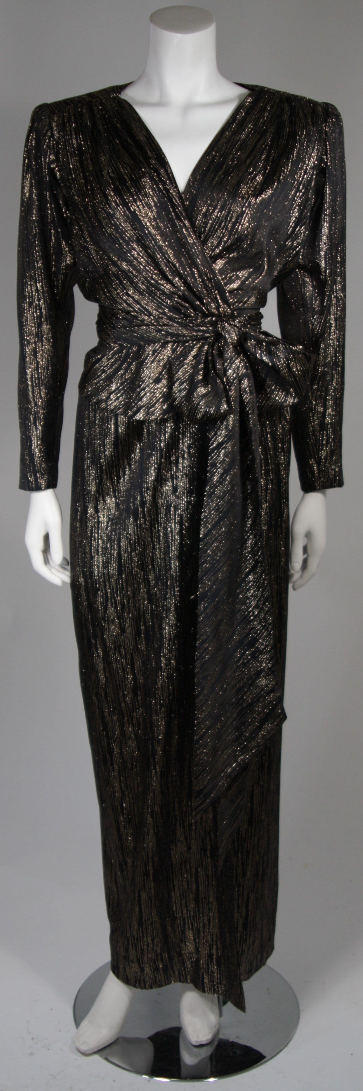 This Nolan Miller attributed ensemble is available for viewing at our Beverly Hills Boutique. We offer a large selection of evening gowns and luxury garments.

This set is composed of a black and gold silk lame. The wrap style blouse and skirt are