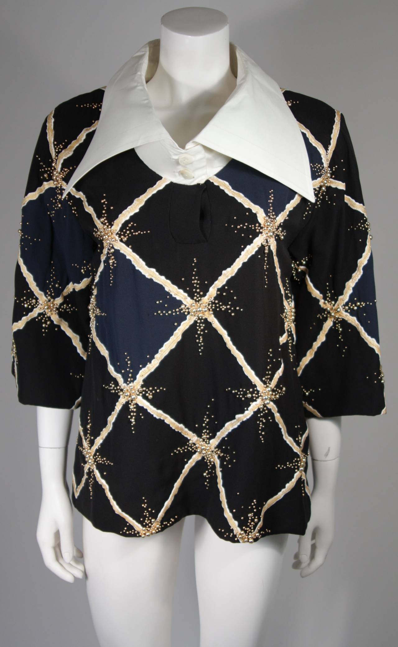Esta blusa de Pierre Balmain está confeccionada en seda estampada en azul marino, negro y blanco con adornos. El cuello de lino está fusionado para conseguir un efecto tridimensional, que hace que se asiente correctamente. Los adornos son pequeñas