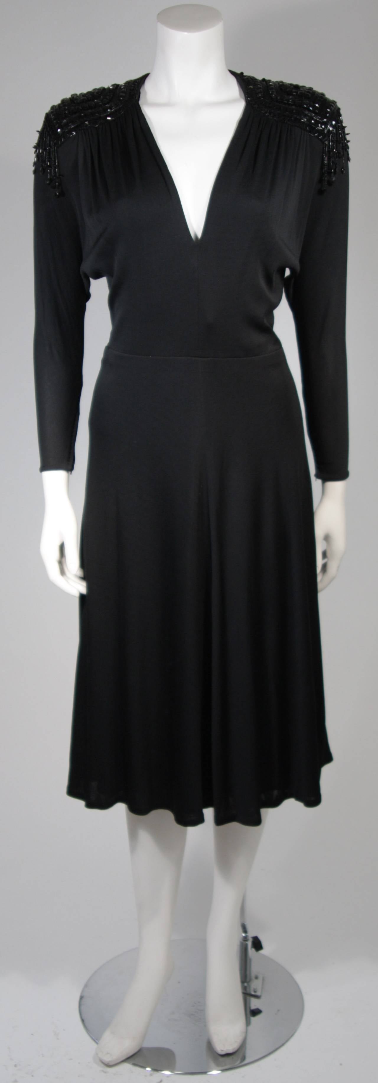 This Nolan Miller attributed dress is composed of a black jersey with embellished shoulders. The wonderful bat-wing style sleeves are accented with large black adornments. There is a center back zipper for ease of access. In excellent condition.