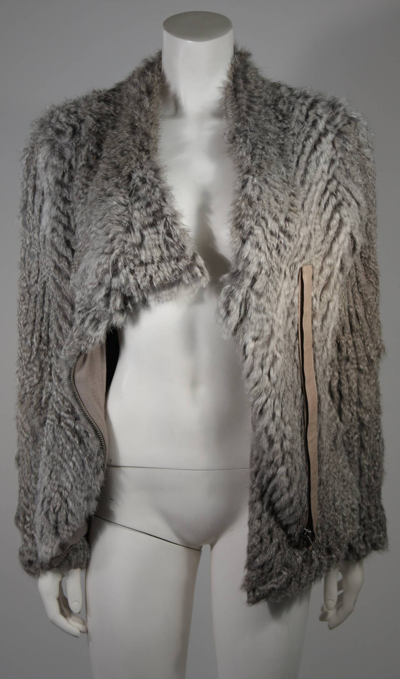 This Helmut Lang sweater is available for viewing at our Beverly Hills Boutique. We offer a large selection of evening gowns and luxury garments.

This sweater is composed of a grey rabbit fur and features an asymmetrical center front zipper. Made