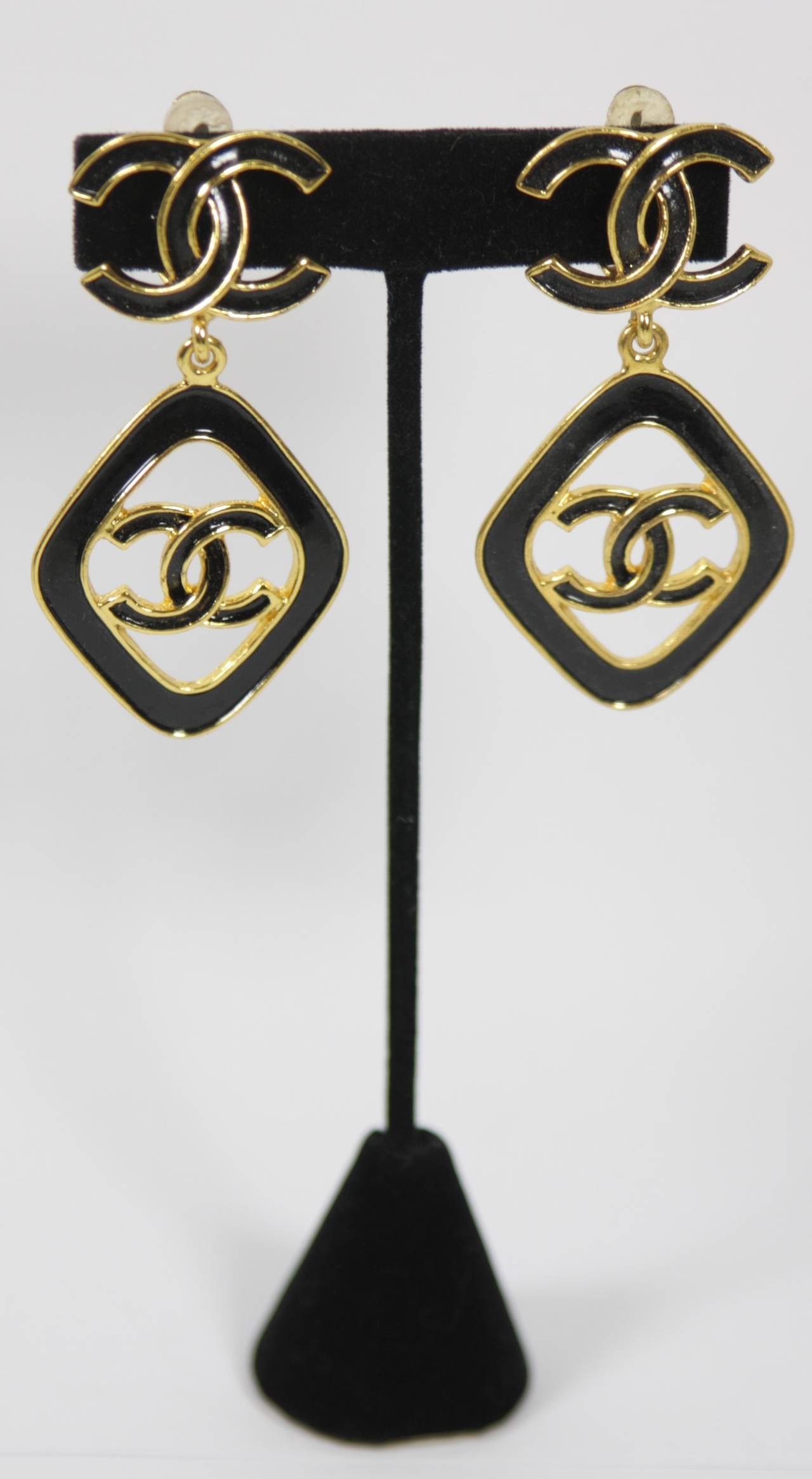 These Chanel earrings are available for viewing at our Beverly Hills Boutique. We offer a large selection of evening gowns and luxury garments.

The earrings are composed of a gold tone metal and are accented with black enamel. They are clip on
