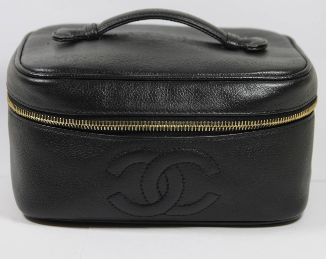 This Chanel cosmetic bag available for viewing at our Beverly Hills Boutique. We offer a large selection of evening gowns and luxury garments.

This make up bag is composed of a black Caviar leather. There is a top handle and zipper closure with a