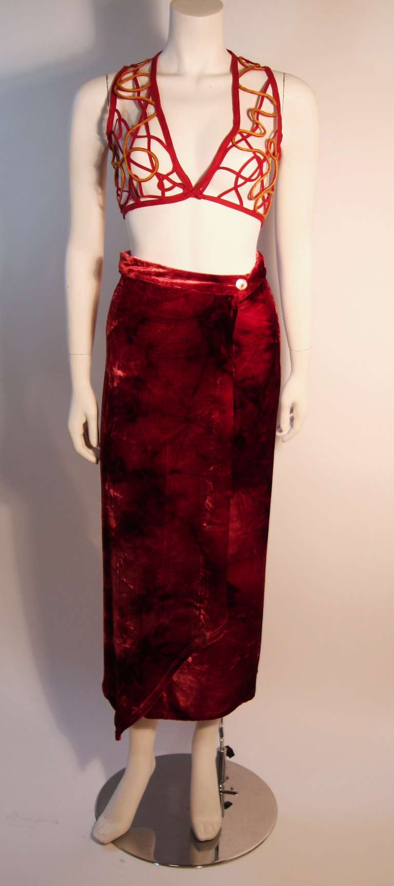 This Ozbek crushed velvet set is very fun. It is a variation of orange and red hues, the red bolero vest has a yellow yarn detail, and the skirt features a wrap detail closure. 

Measurements (Approximate):
Skirt 
Waist: 25