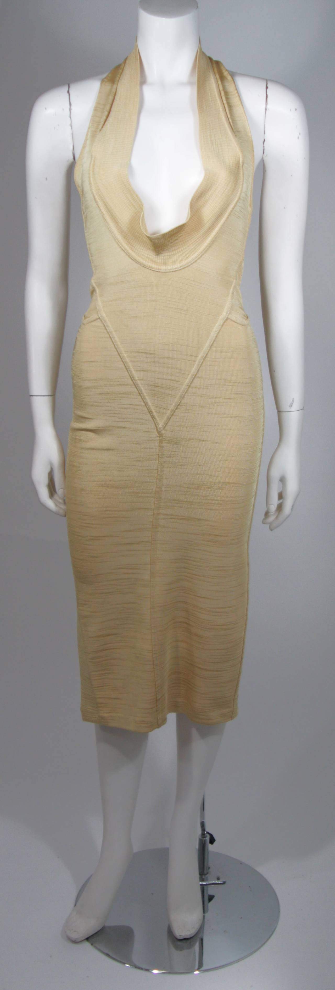 This vintage Alaia dress is available for viewing at our Beverly Hills Boutique. We offer a large selection of evening gowns and luxury garments.

This dress is composed of a gold metallic elastic and features body contouring seams. The plunge