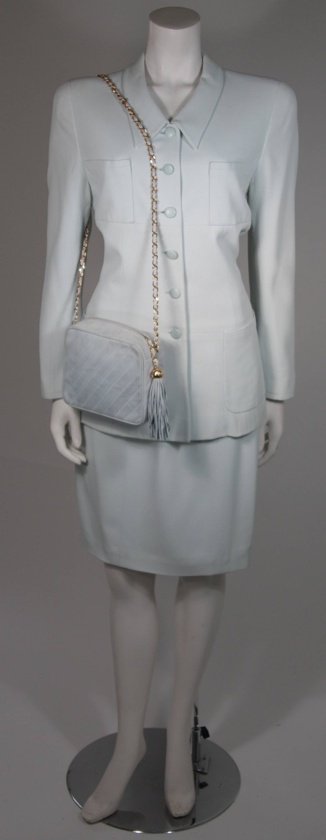 This Chanel suit is available for viewing at our Beverly Hills Boutique. We offer a large selection of evening gowns and luxury garments.

This skirt suit is composed of a light blue fabric and features a classic silhouette. The jacket has four