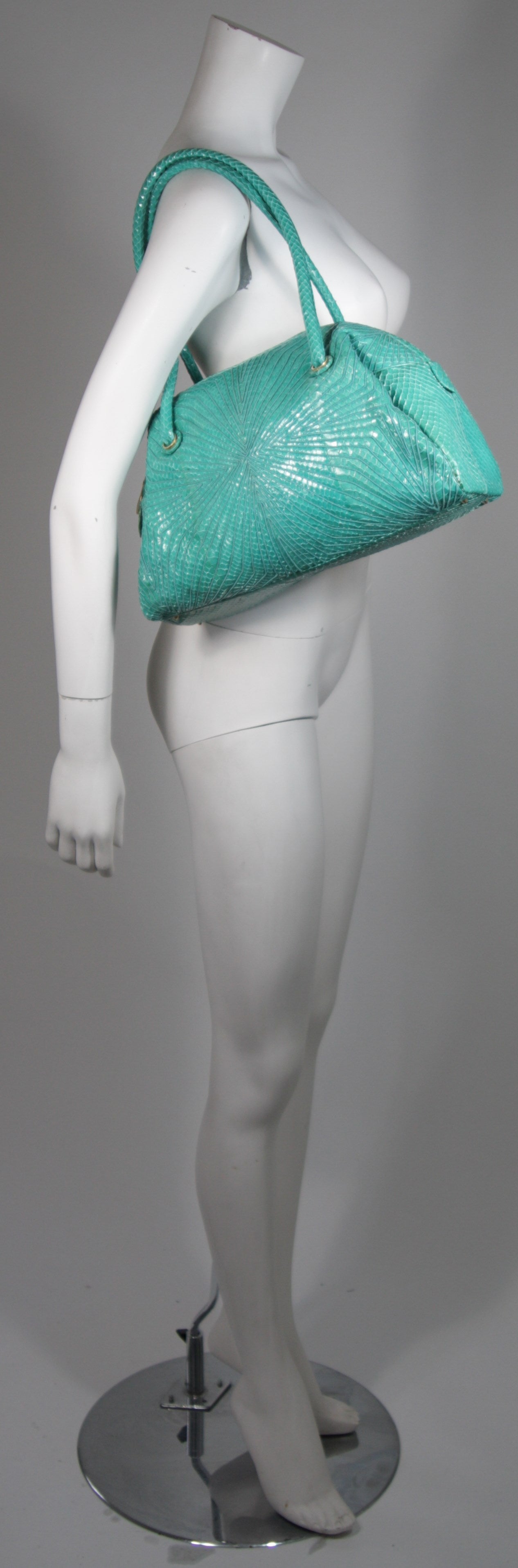 This vintage Judith Leiber is available for viewing at our Beverly Hills Boutique. We offer a large selection of evening gowns and luxury garments.

This handbag is composed of a turquoise snake skin. The handbag has a bowler shape with double