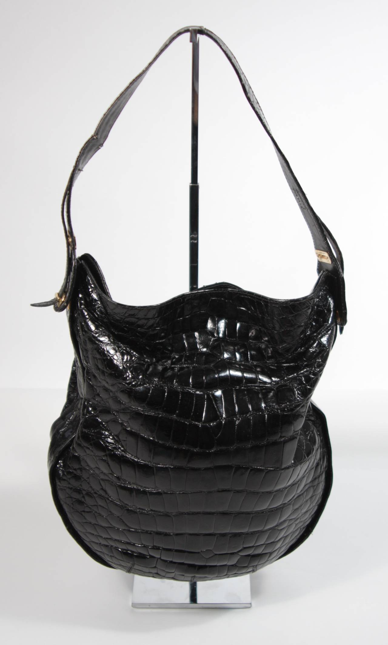 This Charles Jourdan handbag is available for viewing at our Beverly Hills Boutique. We offer a large selection of evening gowns and luxury garments.

This handbag is composed of a black Crocodile and features gold hardware. The strap has an
