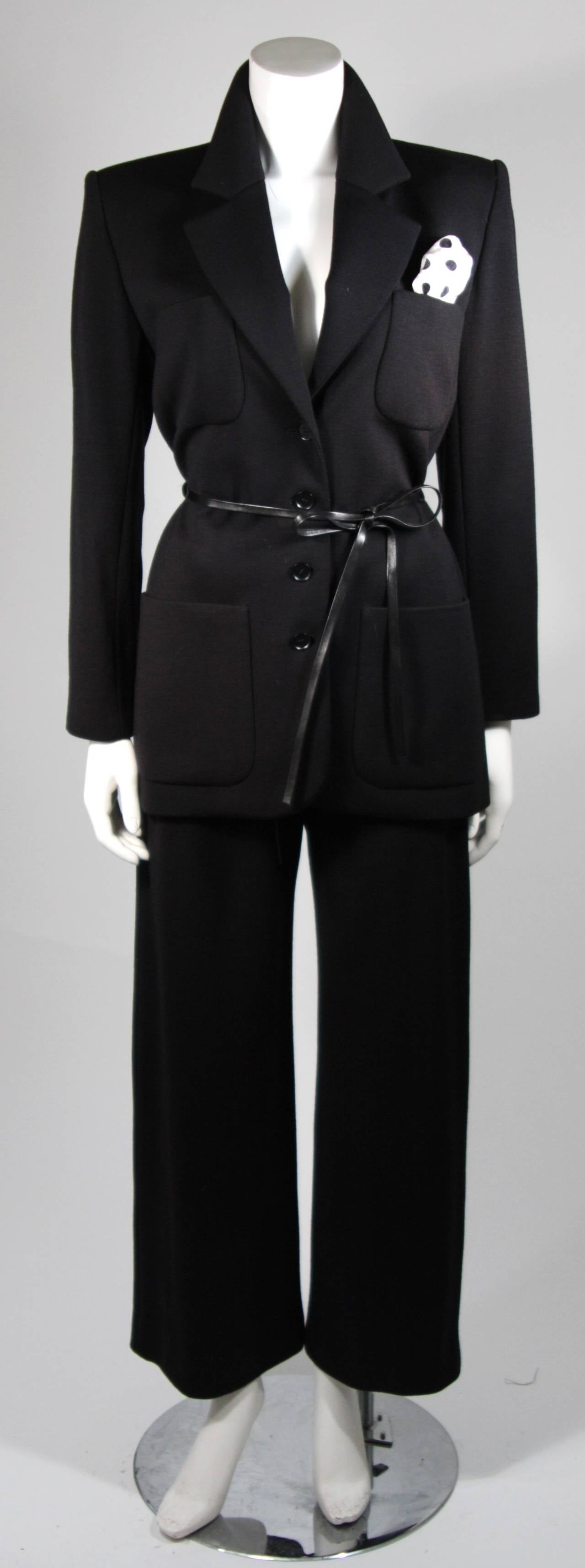 This Yves Saint Laurent design is available for viewing at our Beverly Hills Boutique. We offer a large selection of evening gowns and luxury garments.

This pantsuit ensemble is composed of a black wool blend. The set features leather accents as