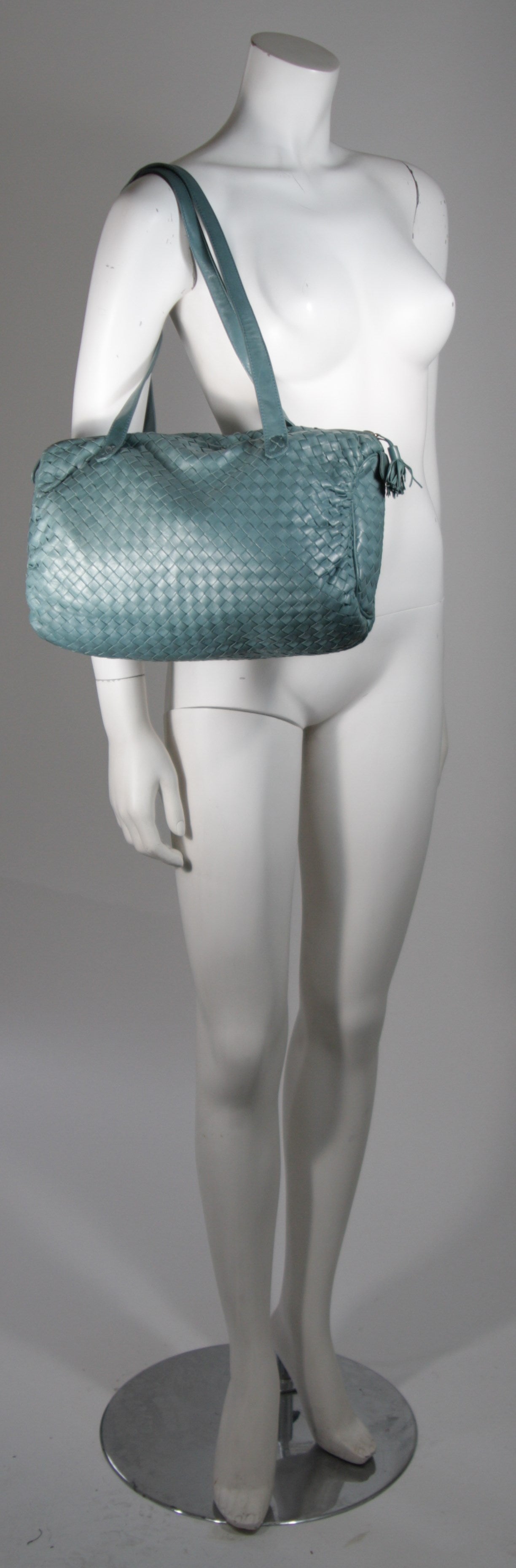 This vintage Bottega Veneta is available for viewing at our Beverly Hills Boutique. We offer a large selection of evening gowns and luxury garments.

This handbag is composed of a supple  teal leather in an interwoven fashion with gold hardware.