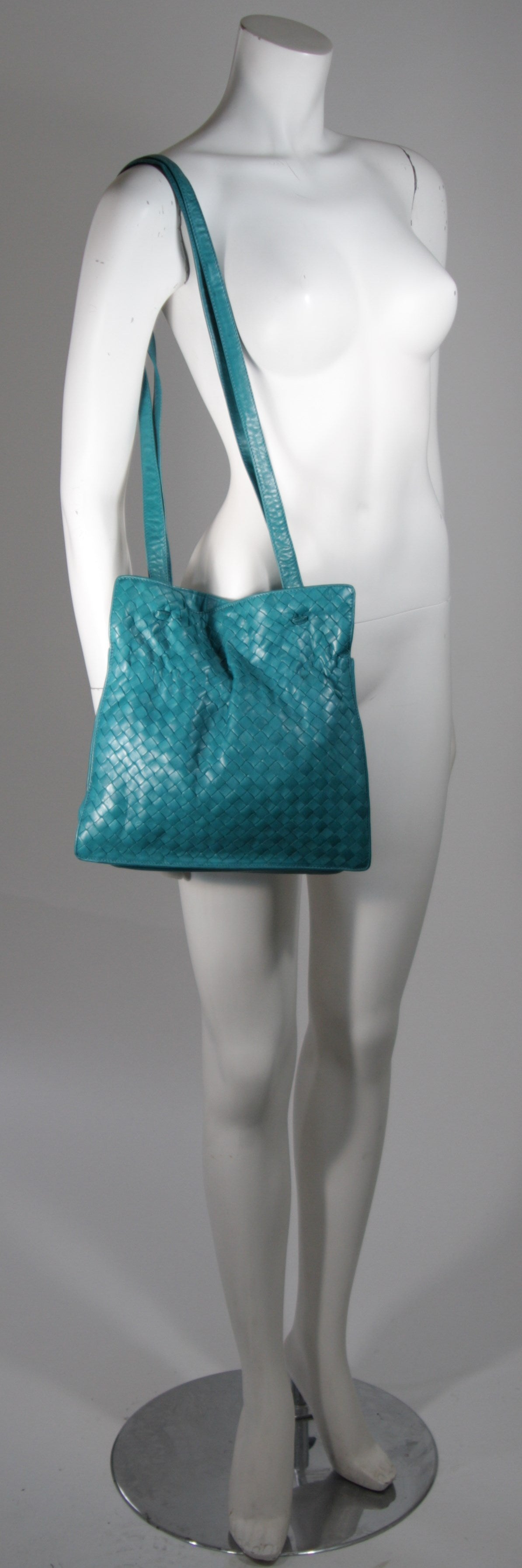 This vintage Bottega Veneta is available for viewing at our Beverly Hills Boutique. We offer a large selection of evening gowns and luxury garments.

This handbag is composed of a supple rich turquoise leather in the classic Bottega Veneta