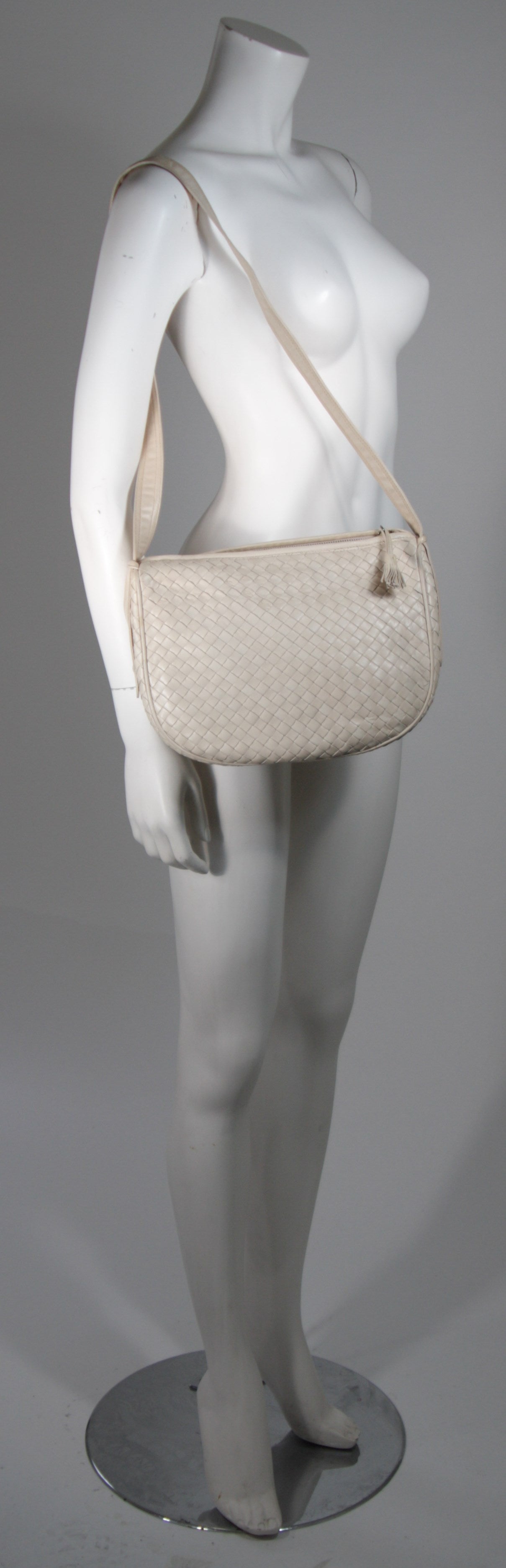 This vintage Bottega Veneta is available for viewing at our Beverly Hills Boutique. We offer a large selection of evening gowns and luxury garments.

This handbag is composed of a supple off white woven leather. The purse features a zipper closure