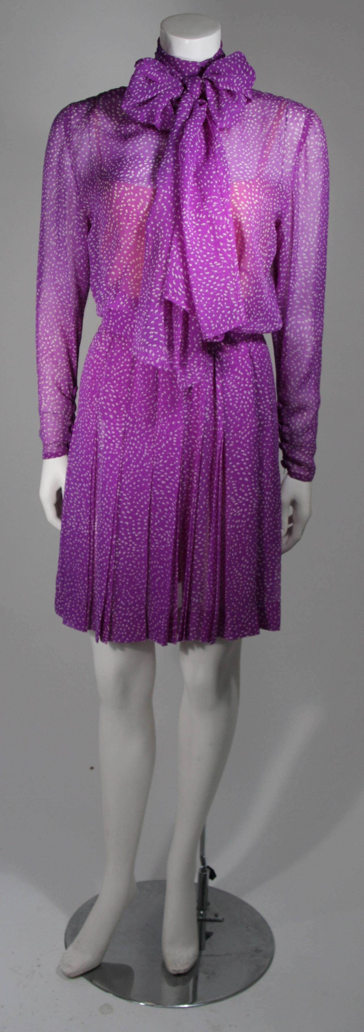 This Givenchy dress is composed of a purple silk chiffon with a white speckle print. There is a neck wrap, which can be worn in a variety of ways. There are center back button closures. Nude slip interior with zipper fastening. In excellent