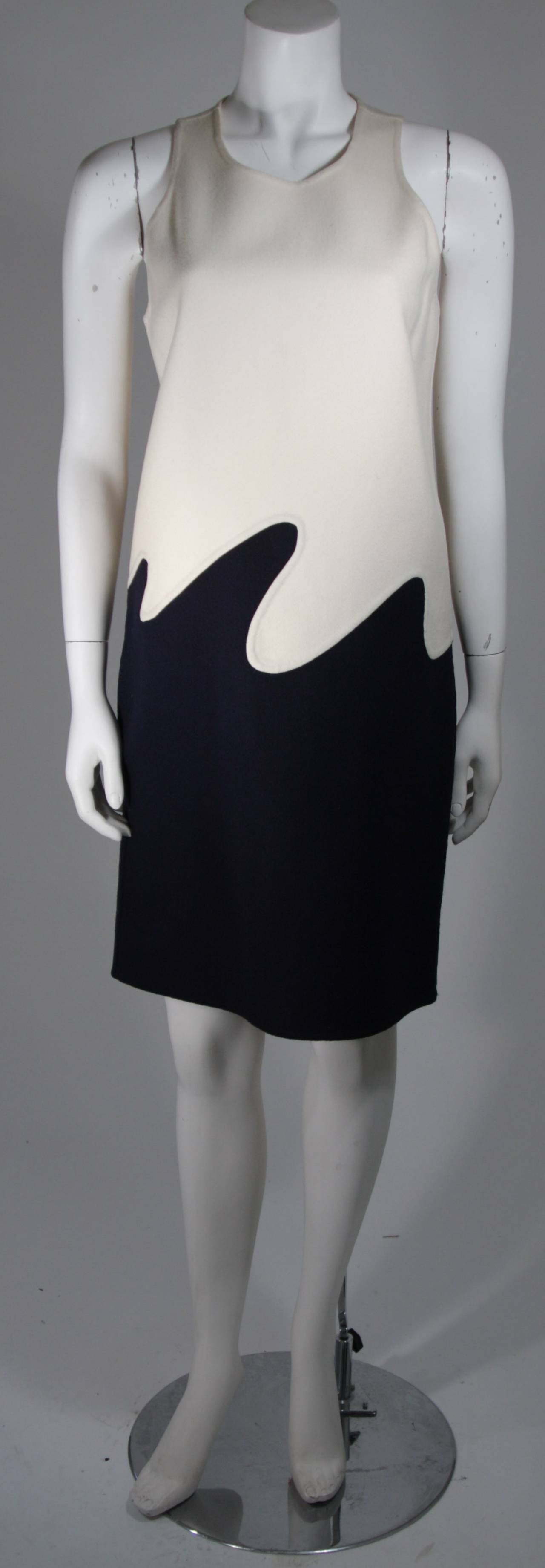 This 1960's dress is composed of medium weight felted wool in a cream and navy color story. The wonderful shift style design is complimented by the wave conjoining seam line construction, merging and melding the contrasting hues. There is a center