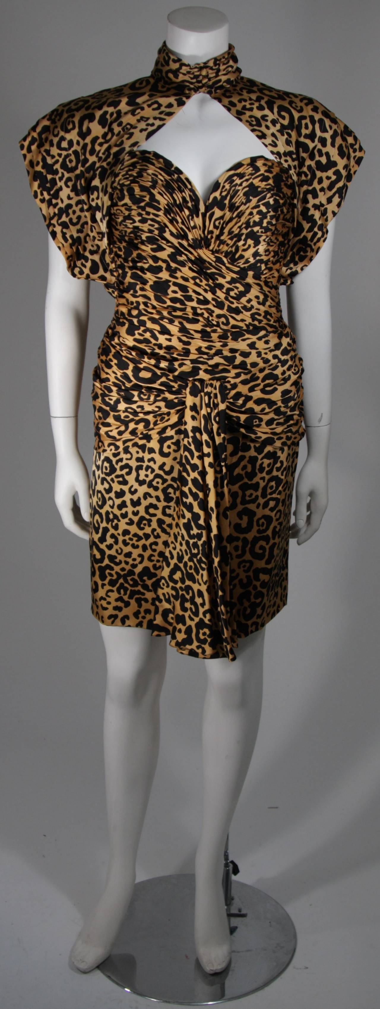 This Vicky Tiel ensemble is composed animal print silk in gold and black. The dress is a rouched drape style bustier dress with a side zipper. The caplet features a mock neck with buttons. Made in France. 

**Please cross-reference measurements