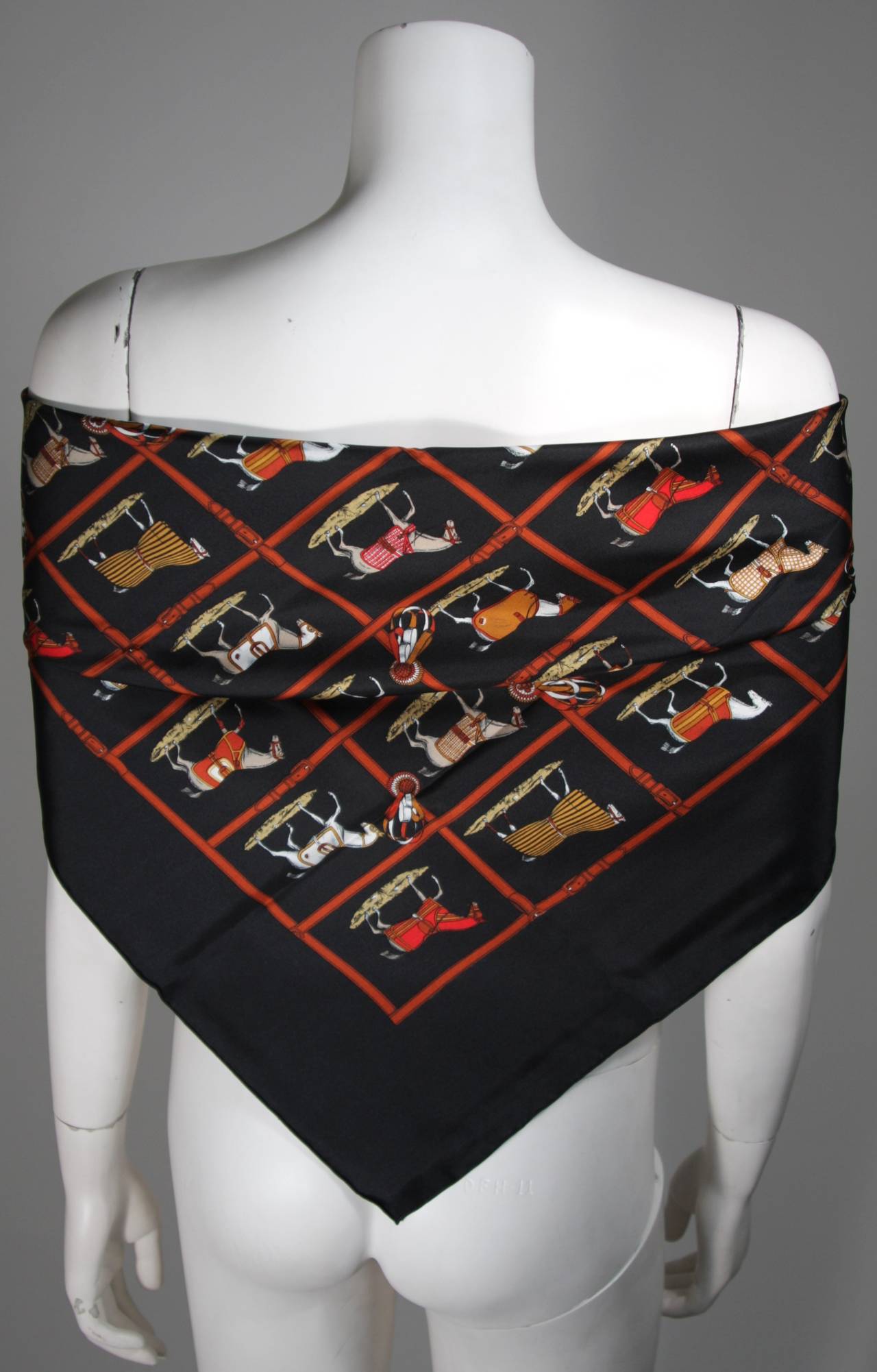 Hermes hand rolled black silk twill scarf with horses before the big race. 
Buckle strap detailed checker board pattern with earth tone ribbons.
In excellent condition. 
31 inches by 31 inches
Made in France
100% Silk
Hermes Box included
This