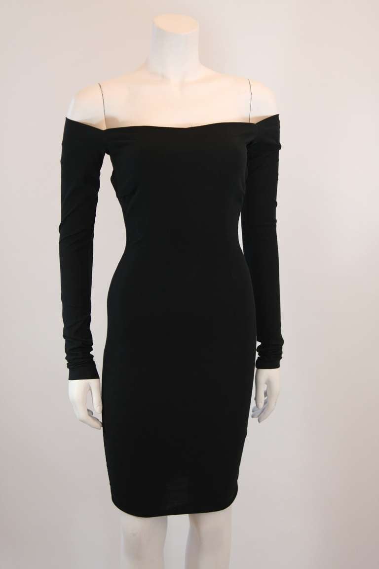 This is an exceptionally designed curve loving Dolce and Gabbana dress. It features off the shoulder sleeves and an open back with zipper closure.The stretch silk blend accentuates this little black dress on the female form in true Dolce and Gabbana