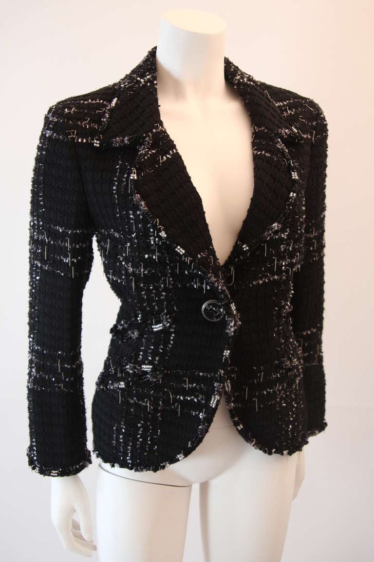 This is an excellent and sharp blazer designed by Chanel. It Features a front button closure, two front pockets, and cream silk detail at the sleeve. The trademark black metallic Chanel fabric is infused with suspended chain links and hand applied