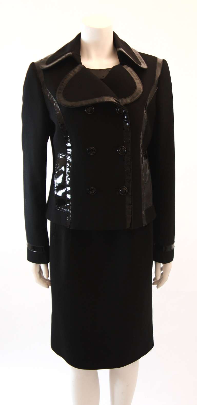 This is a Dolce and Gabbana black dress suit with jacket. The suit jacket and shift dress have a black patent trim. The jacket is double breasted and features two front pockets. The dress features a zipper closure. 

Measures (approximate)
Jacket